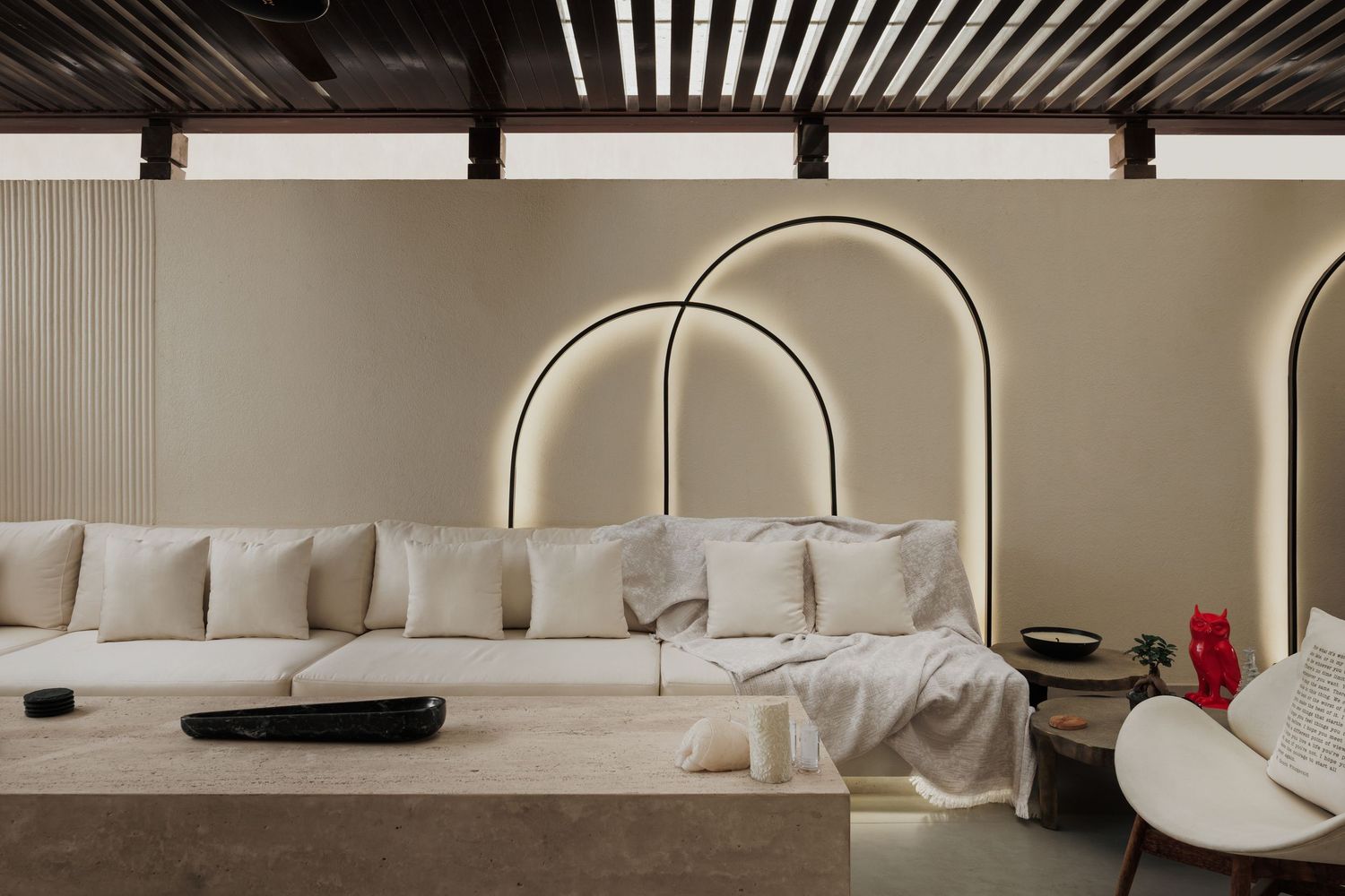 Luxurious beige living room featuring a large sectional sofa beneath a dramatic backlit arch on textured wall.