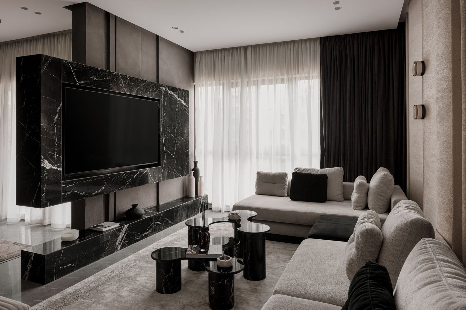 Luxury living room with black marble TV wall, gray sectional sofa, and dark curtains in modern interior design.