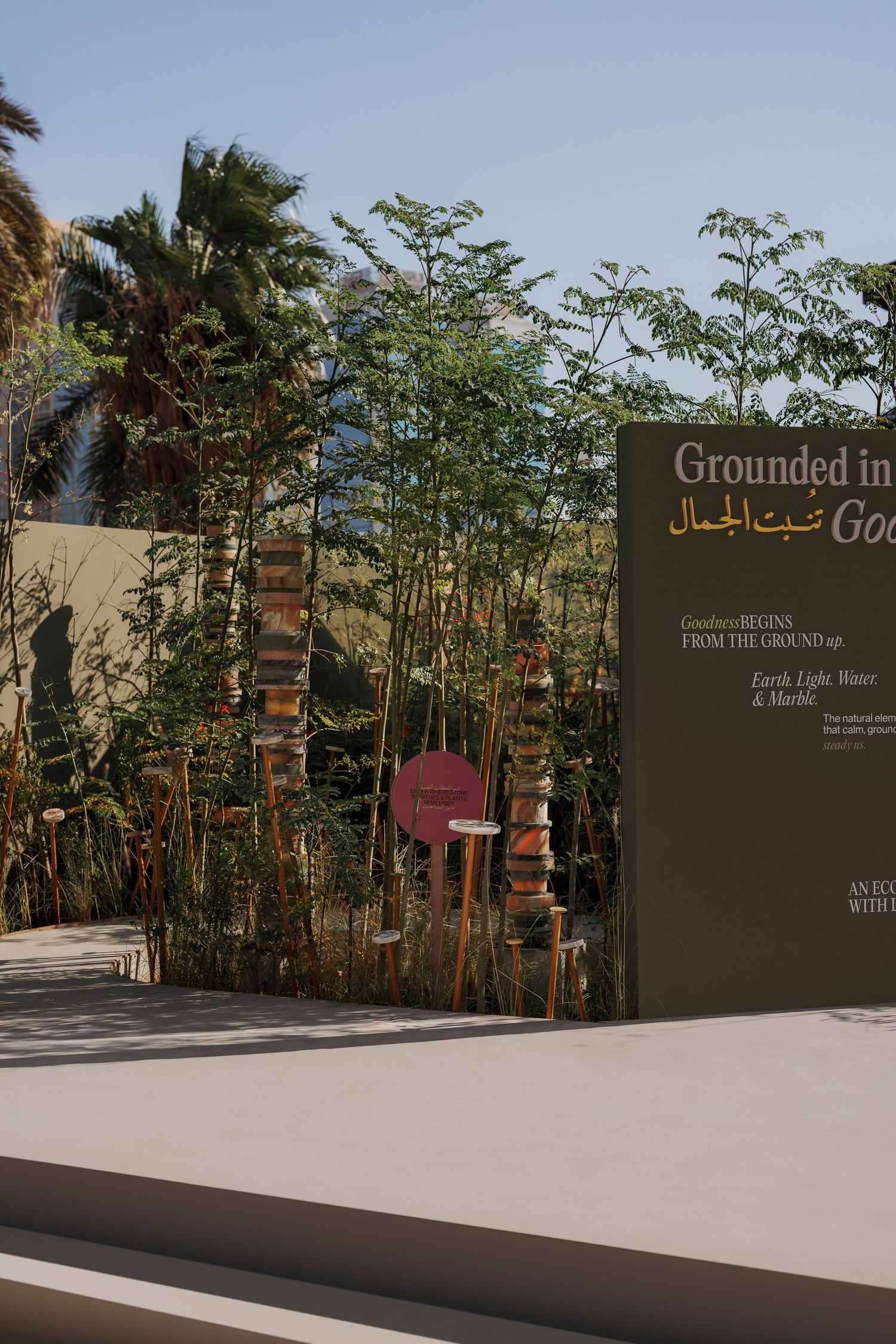 Garden exhibition sign reading Grounded in Good Beauty with bamboo and stacked stone sculptures.
