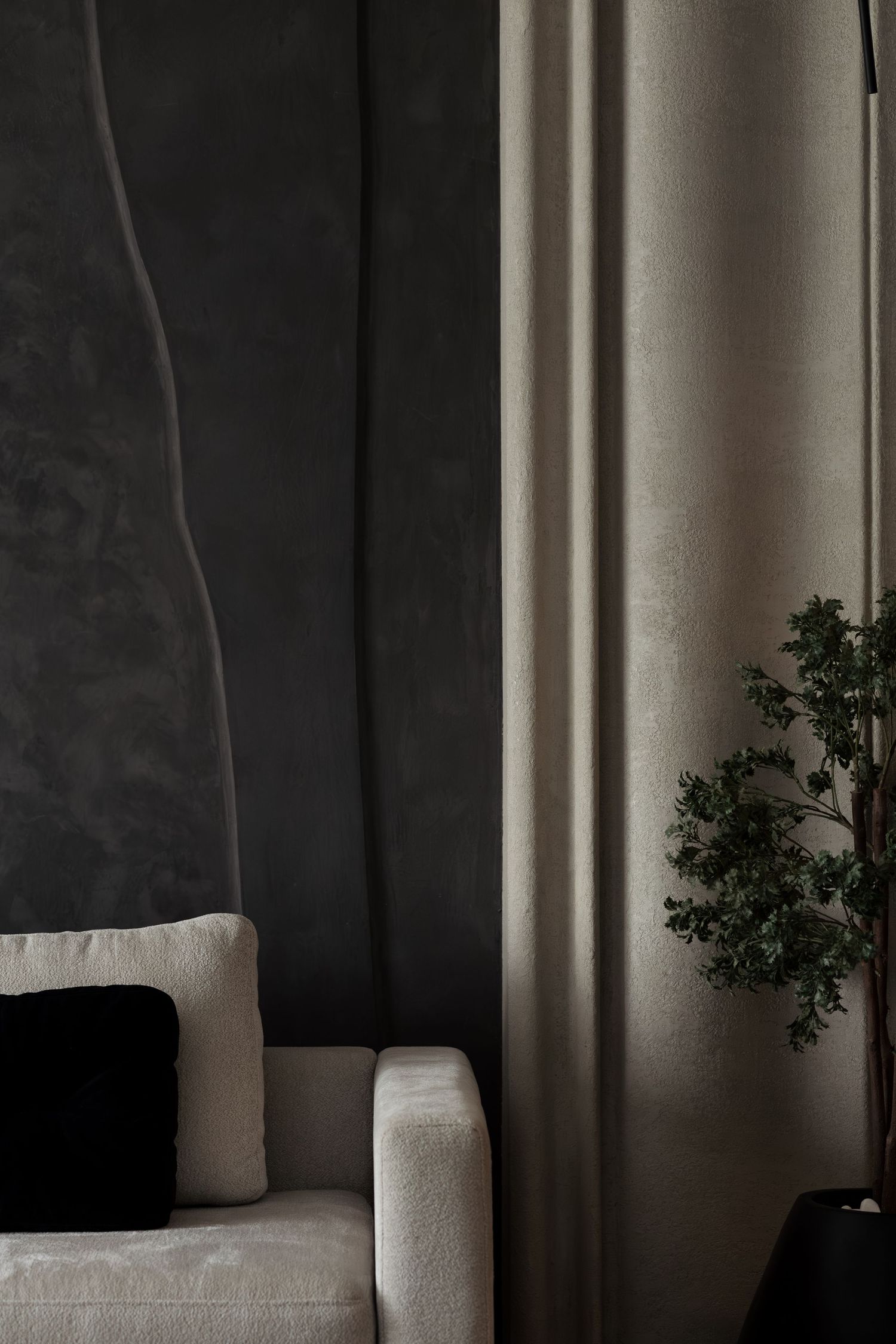 White boucle sofa with black cushion against dark textured accent wall and beige curtain.