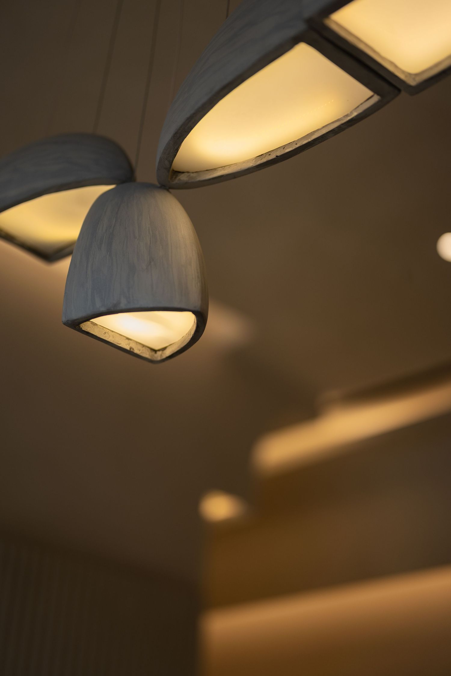 Modern pendant lamp with warm glowing light hanging from decorative ceiling fixture in contemporary interior.