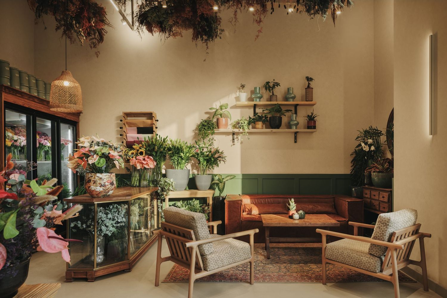 Cozy flower shop lounge with mid-century chairs, hanging botanicals, and a floral display counter.