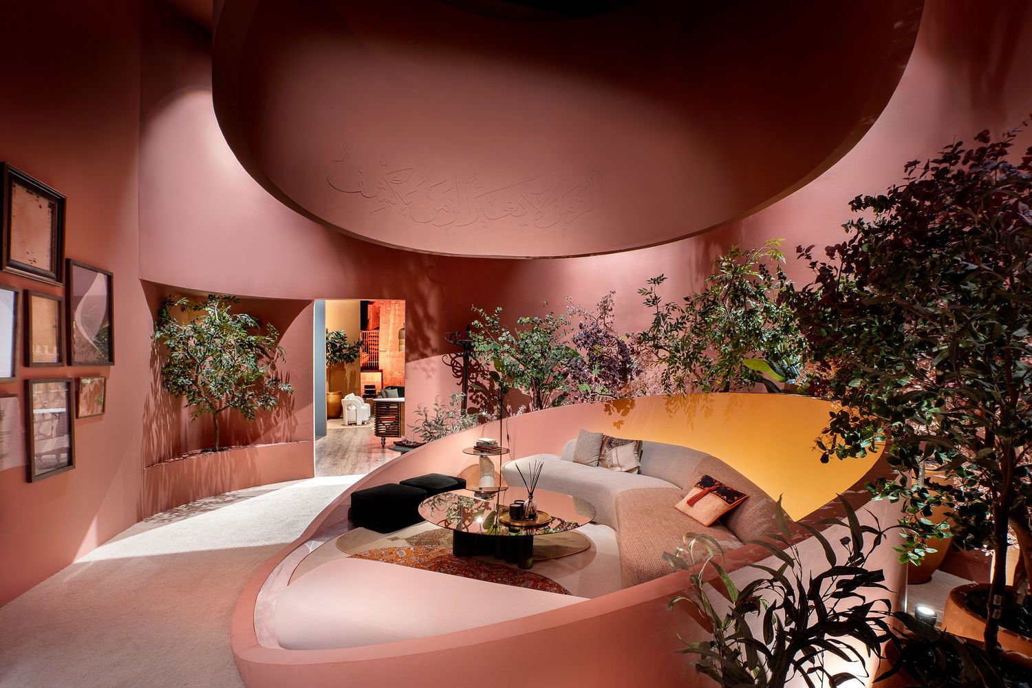 Curved pink interior space with white sofa, indoor trees, and organic architectural design elements.