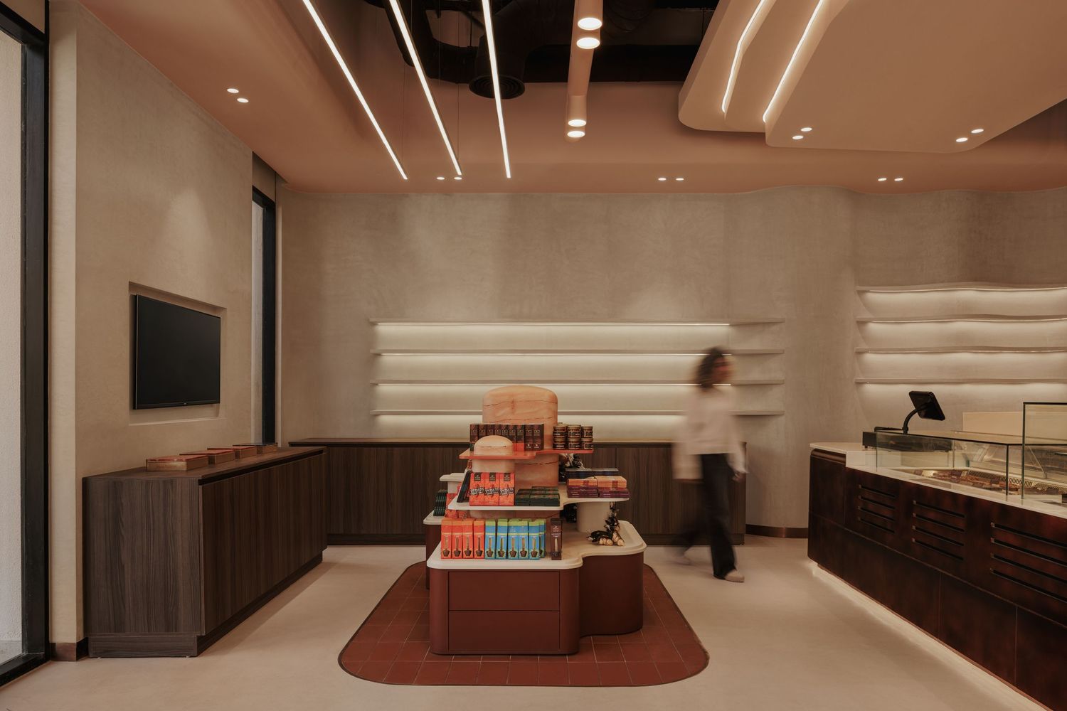 Modern retail interior with warm lighting, central display island, and white shelving.