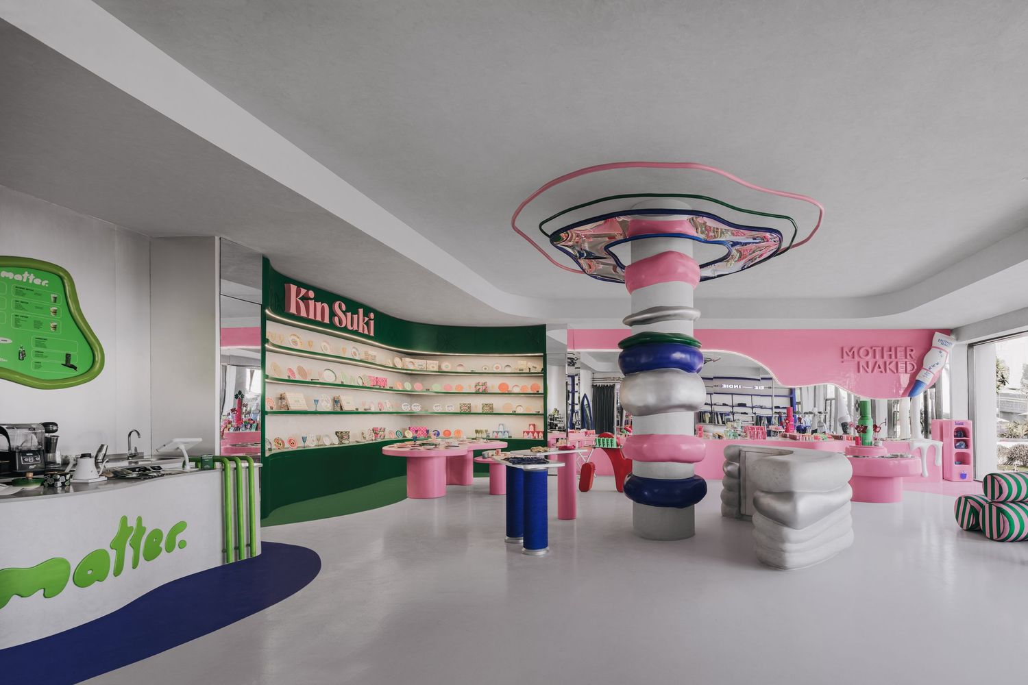 Vibrant modern retail store with pink and green decor, colorful column, and stylish displays in a bright white interior.