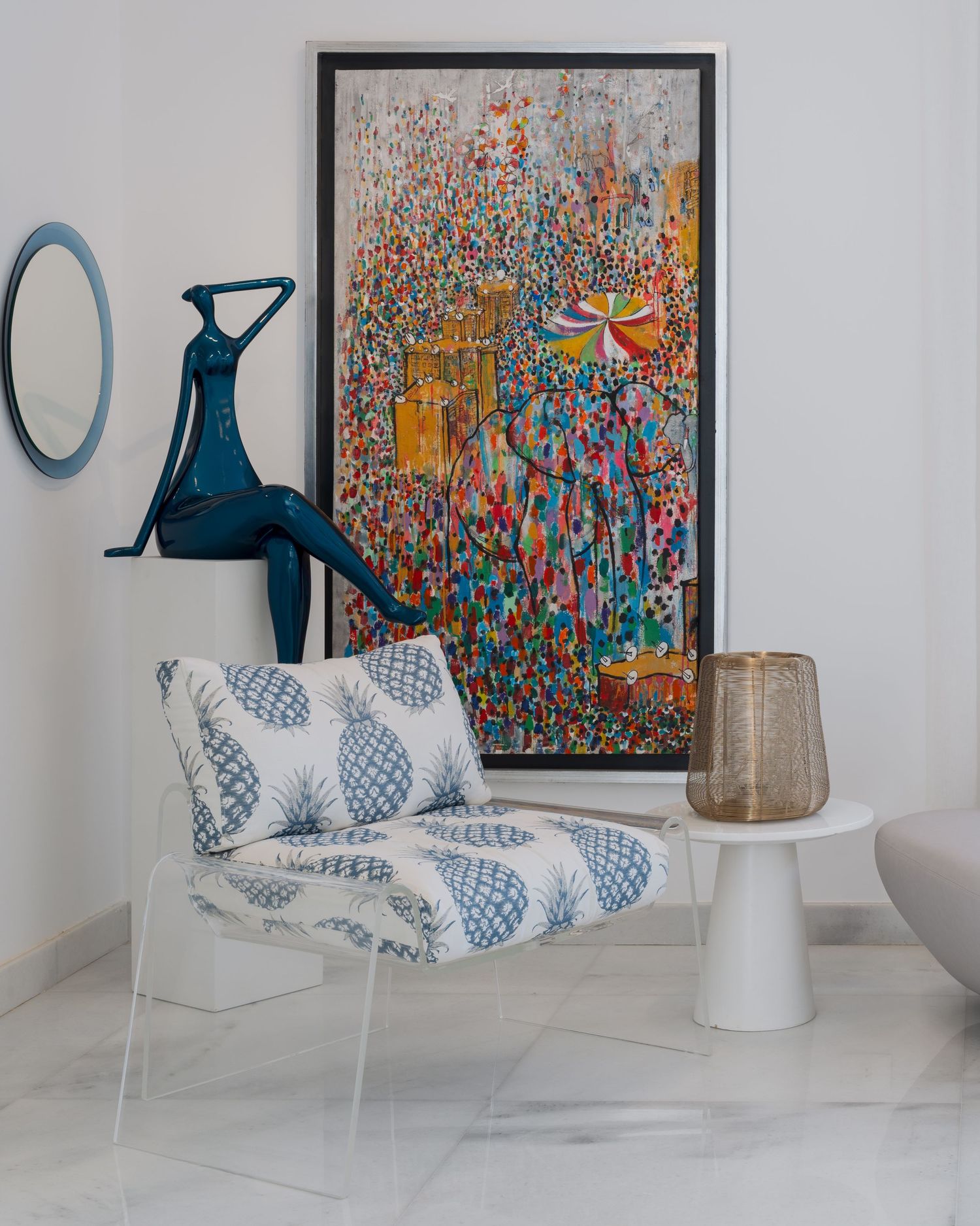 Contemporary interior vignette with colorful abstract art, blue sculpture, patterned accent chair, and marble floor.