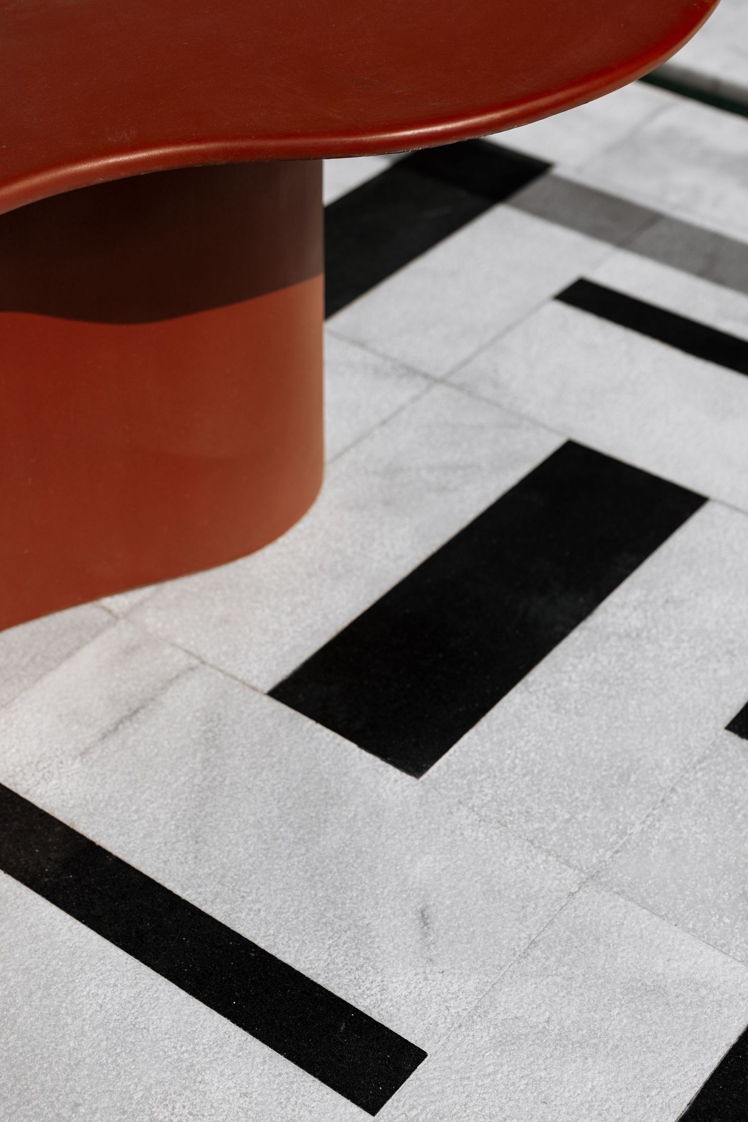 Red table base on bold black and white geometric marble floor tiles.