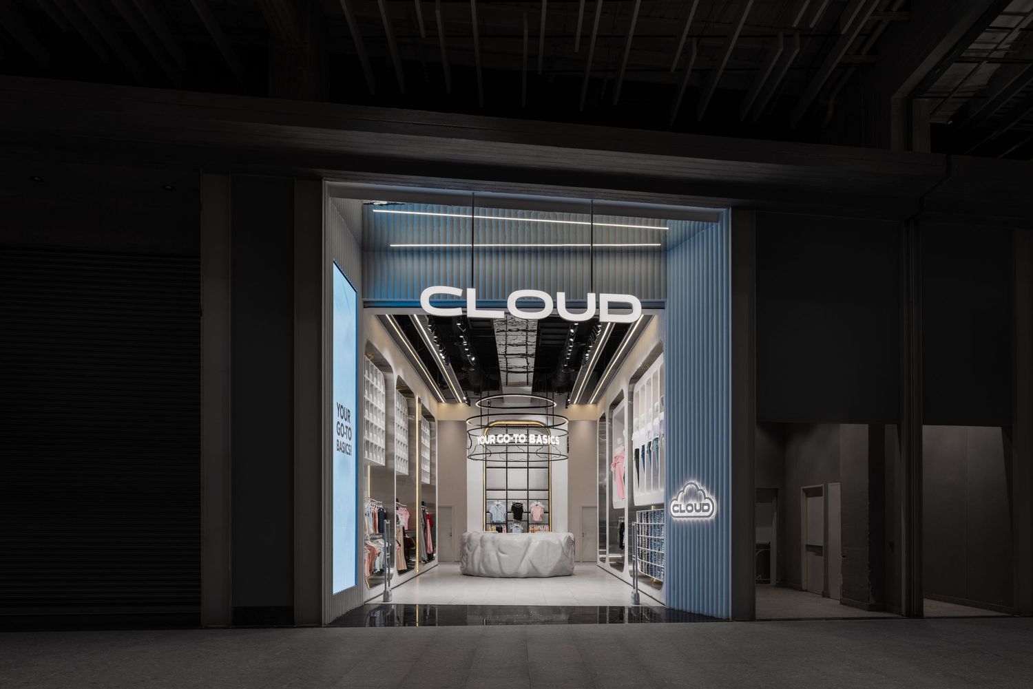 Cloud branded store entrance at night featuring glowing white signage and minimalist interior visible through a wide open facade.