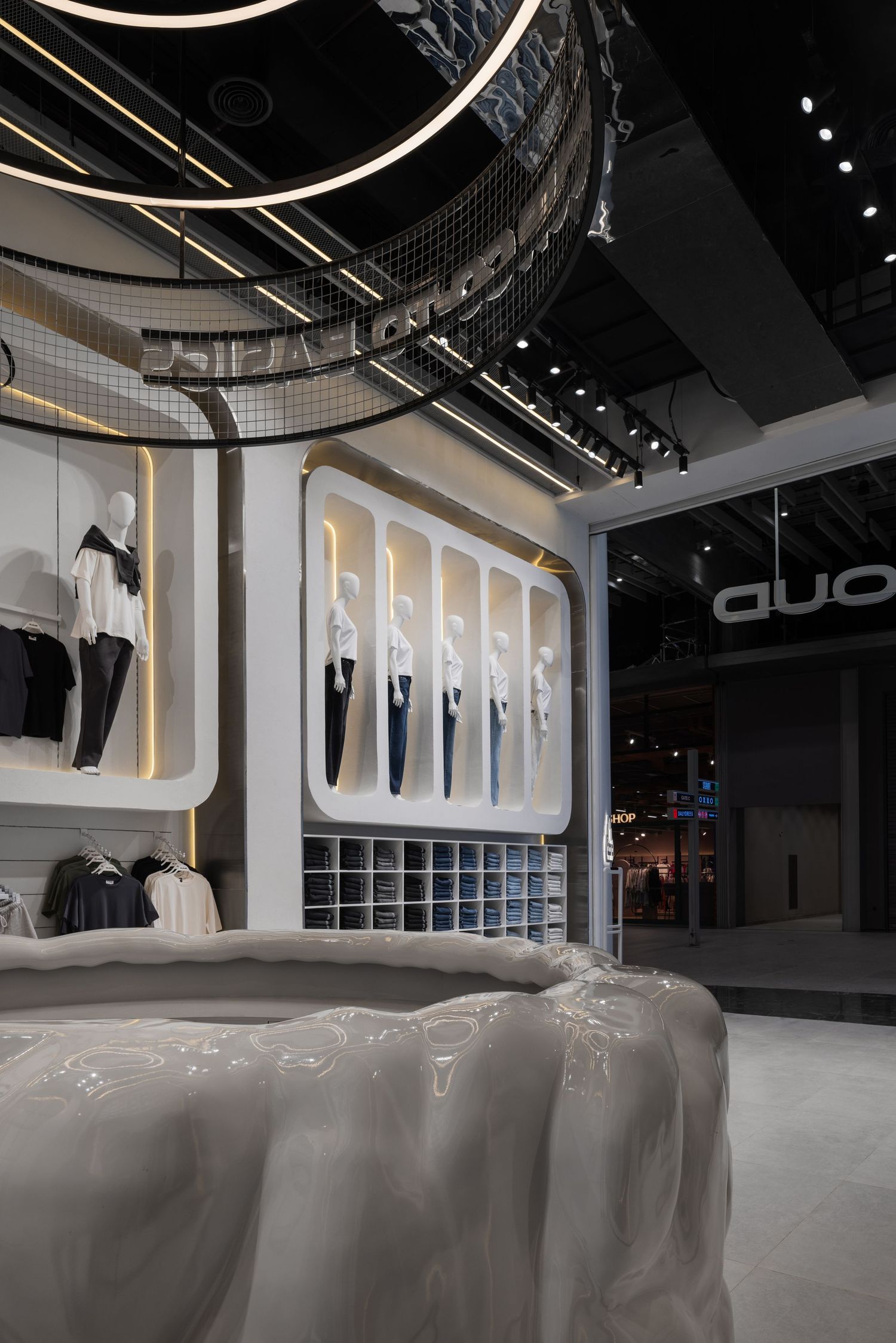 Futuristic retail store interior with white curved display units, illuminated niches, and circular ceiling lighting fixtures.