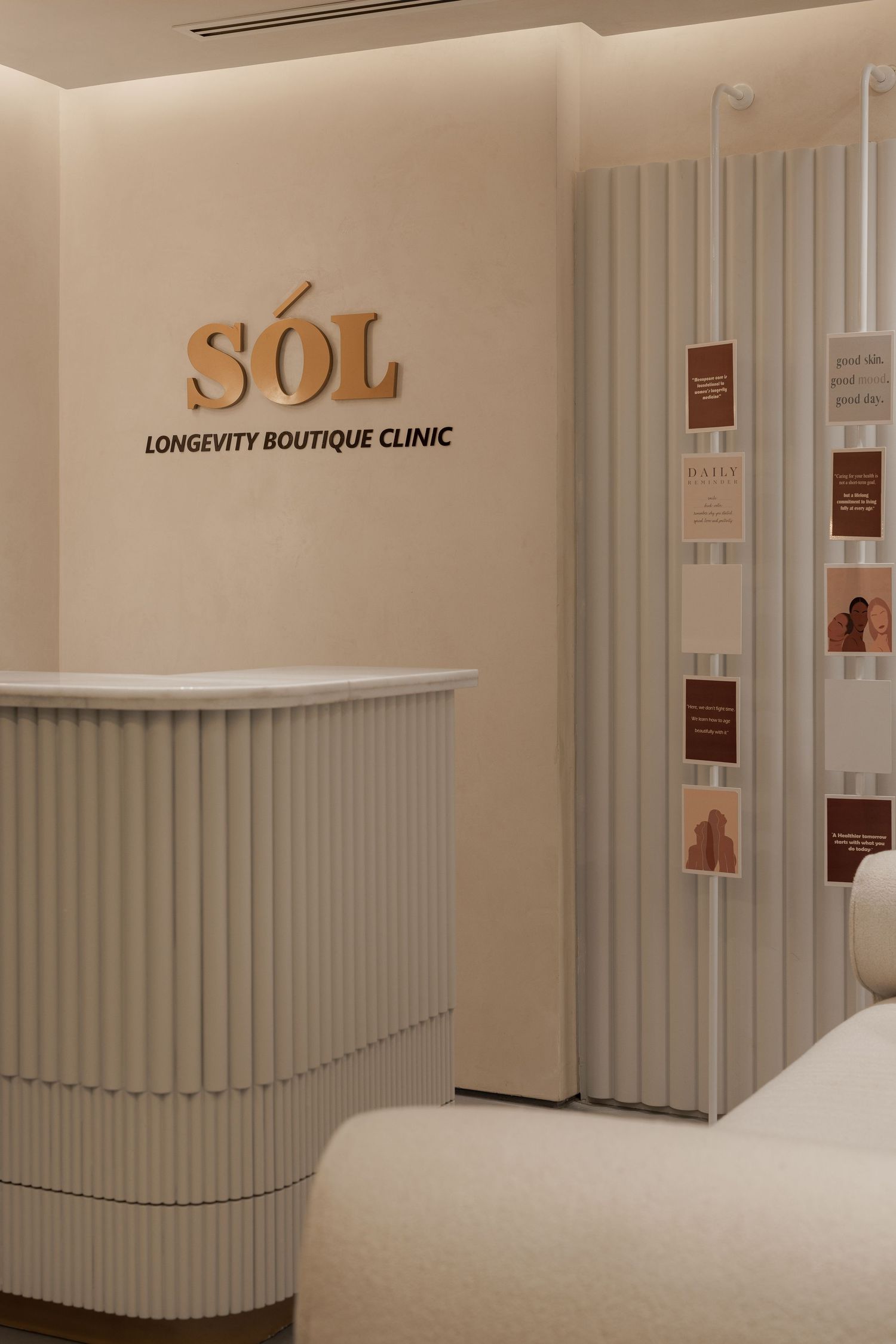 SÓL Longevity Boutique Clinic reception with white fluted desk and warm beige interior design.