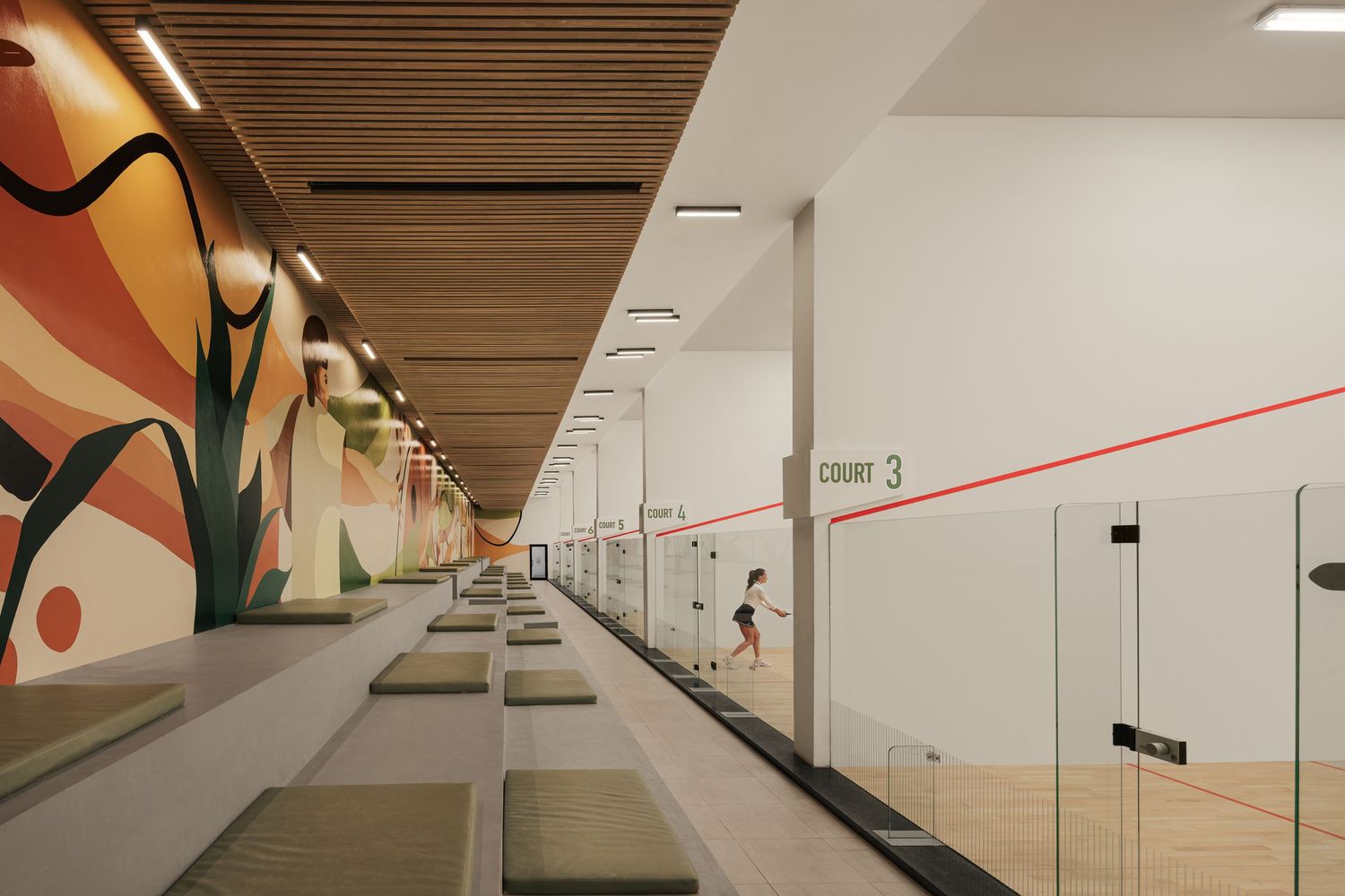 Modern squash court facility with vibrant botanical wall murals and multiple glass-walled courts with wood ceiling.
