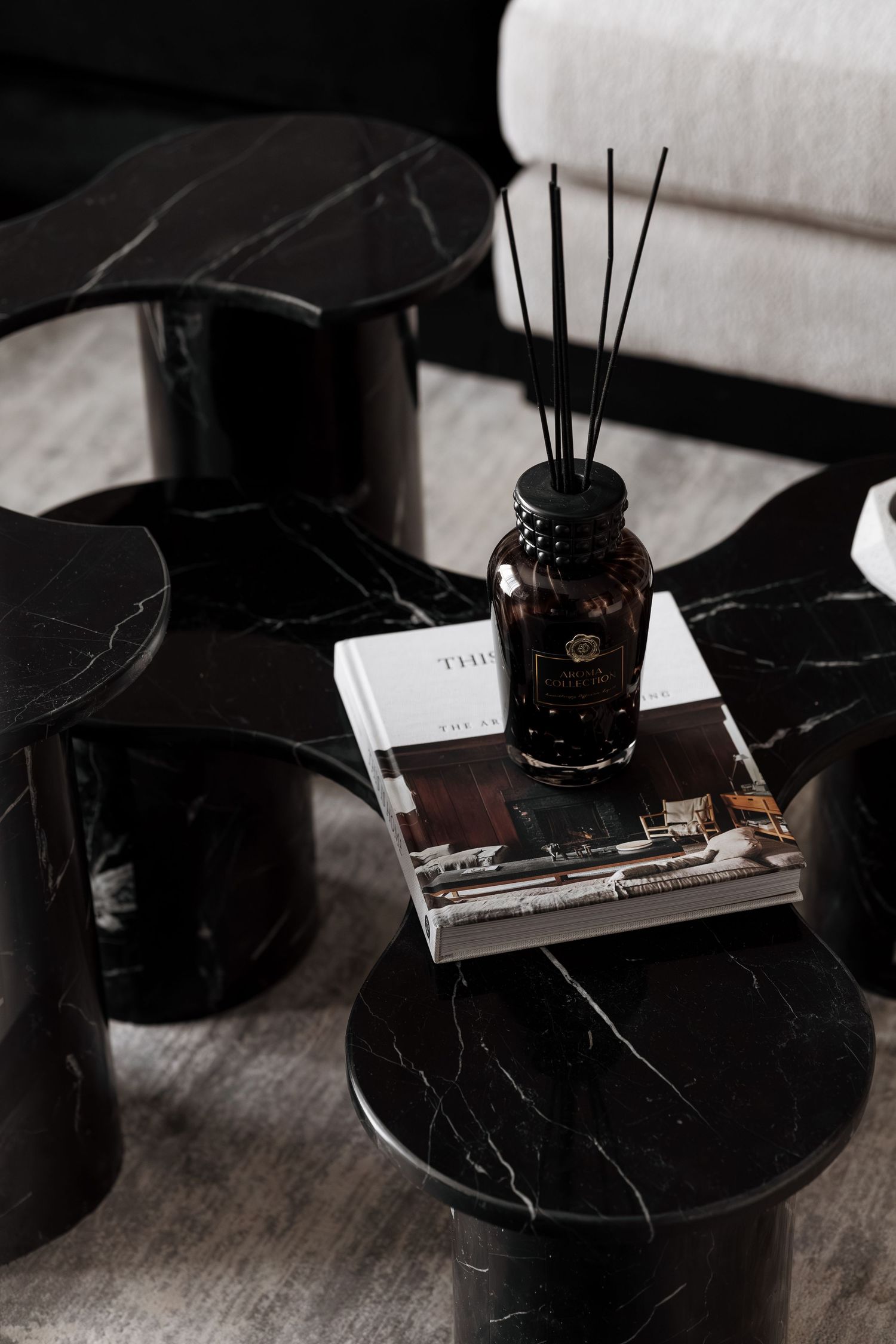 Black marble nesting coffee tables styled with a reed diffuser and coffee table book in a modern interior.