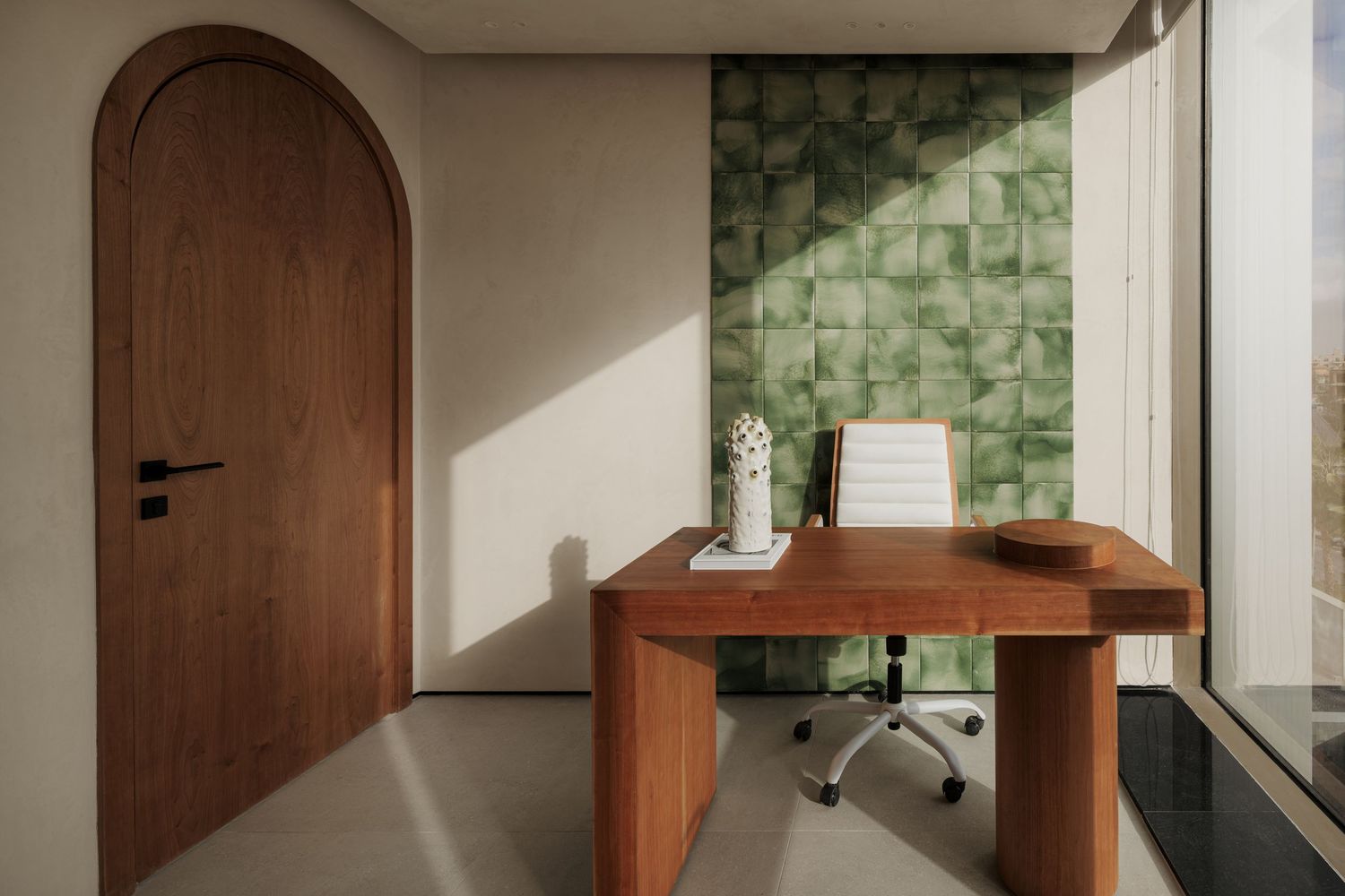 Bright office with arched walnut door, wooden desk, green tiled accent wall, and natural window light.