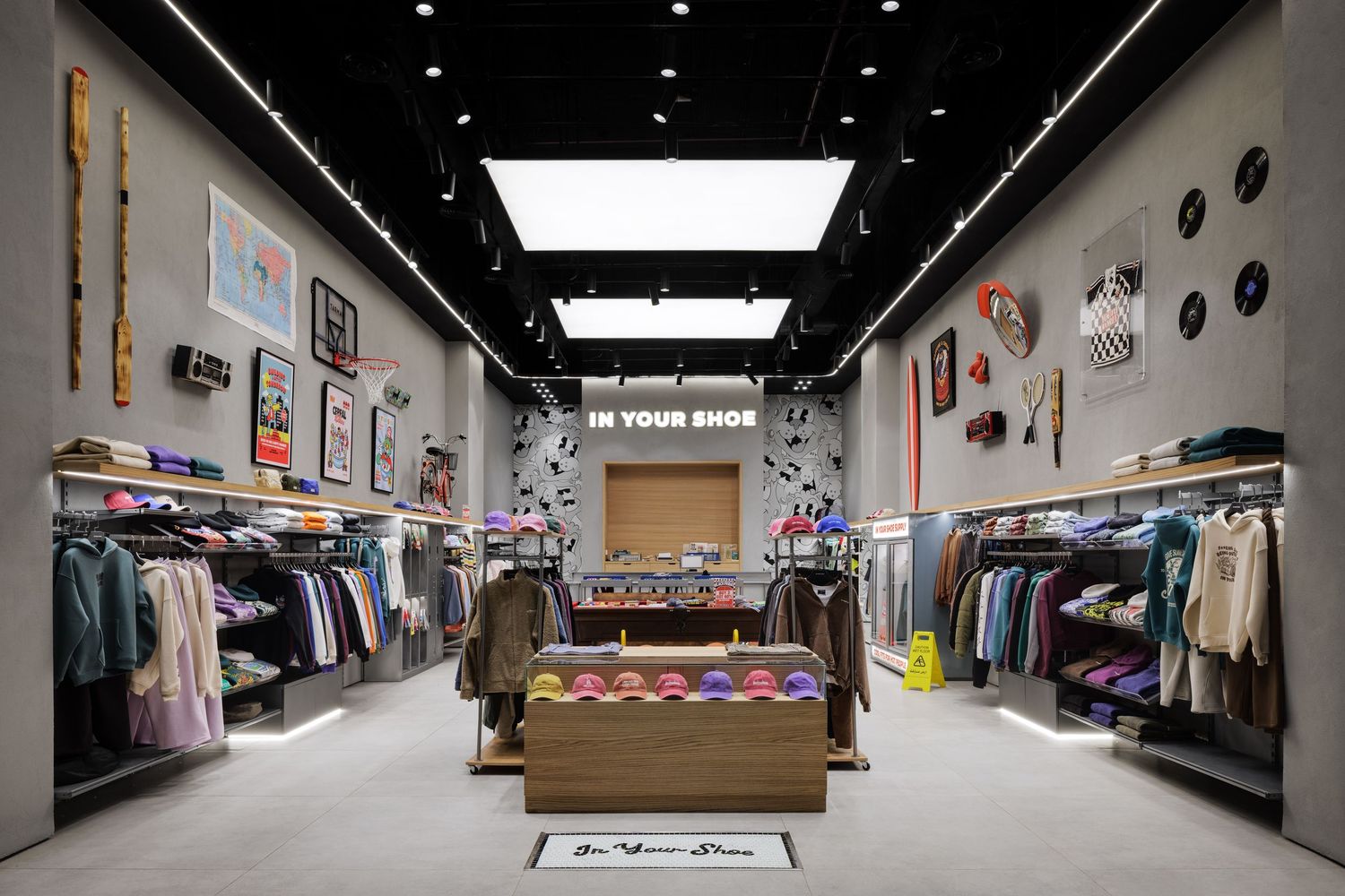 In Your Shoe streetwear store interior featuring clothing racks, hat displays, and urban wall decor.
