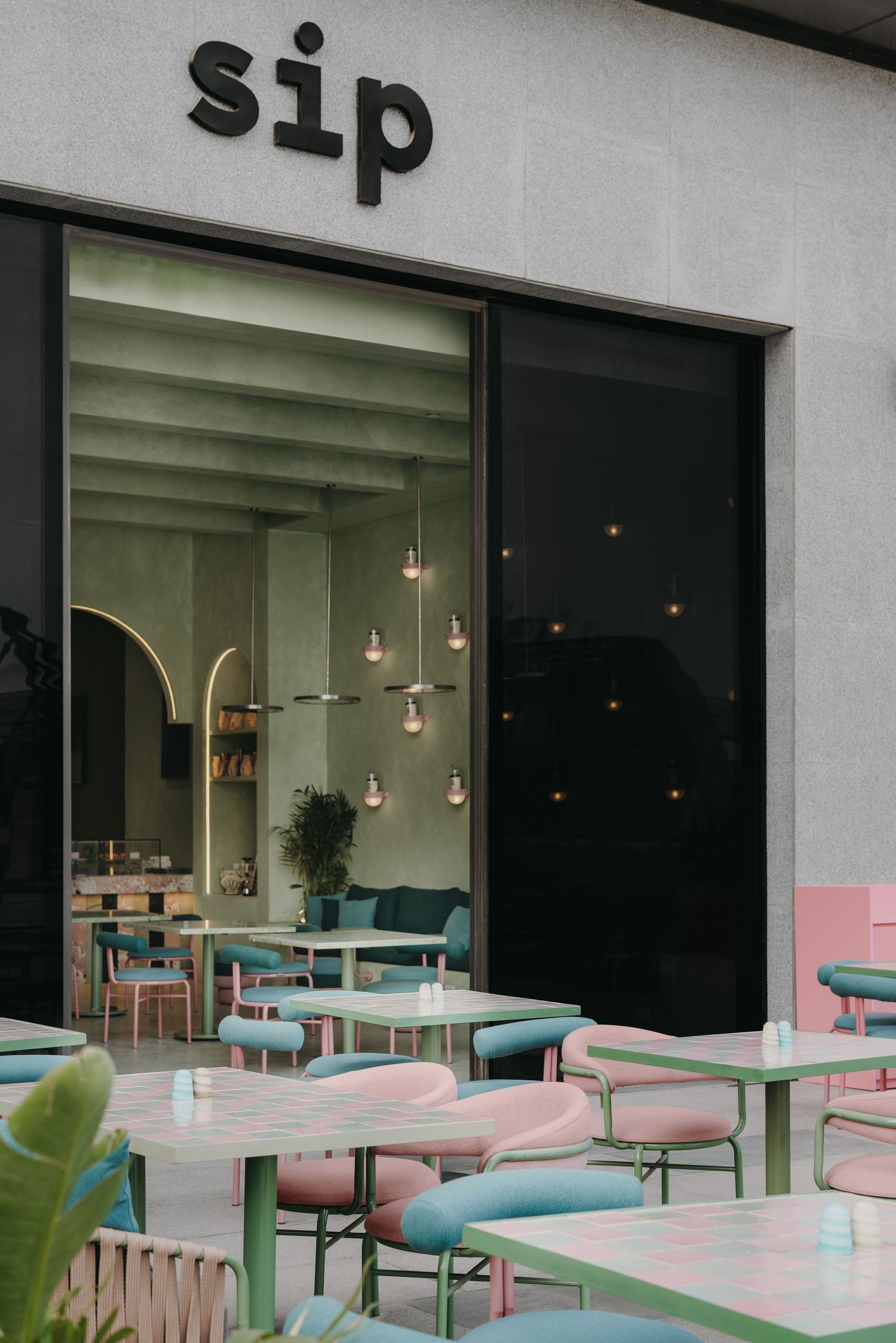 Outdoor patio of Sip cafe with pastel pink and green metal chairs and tables.