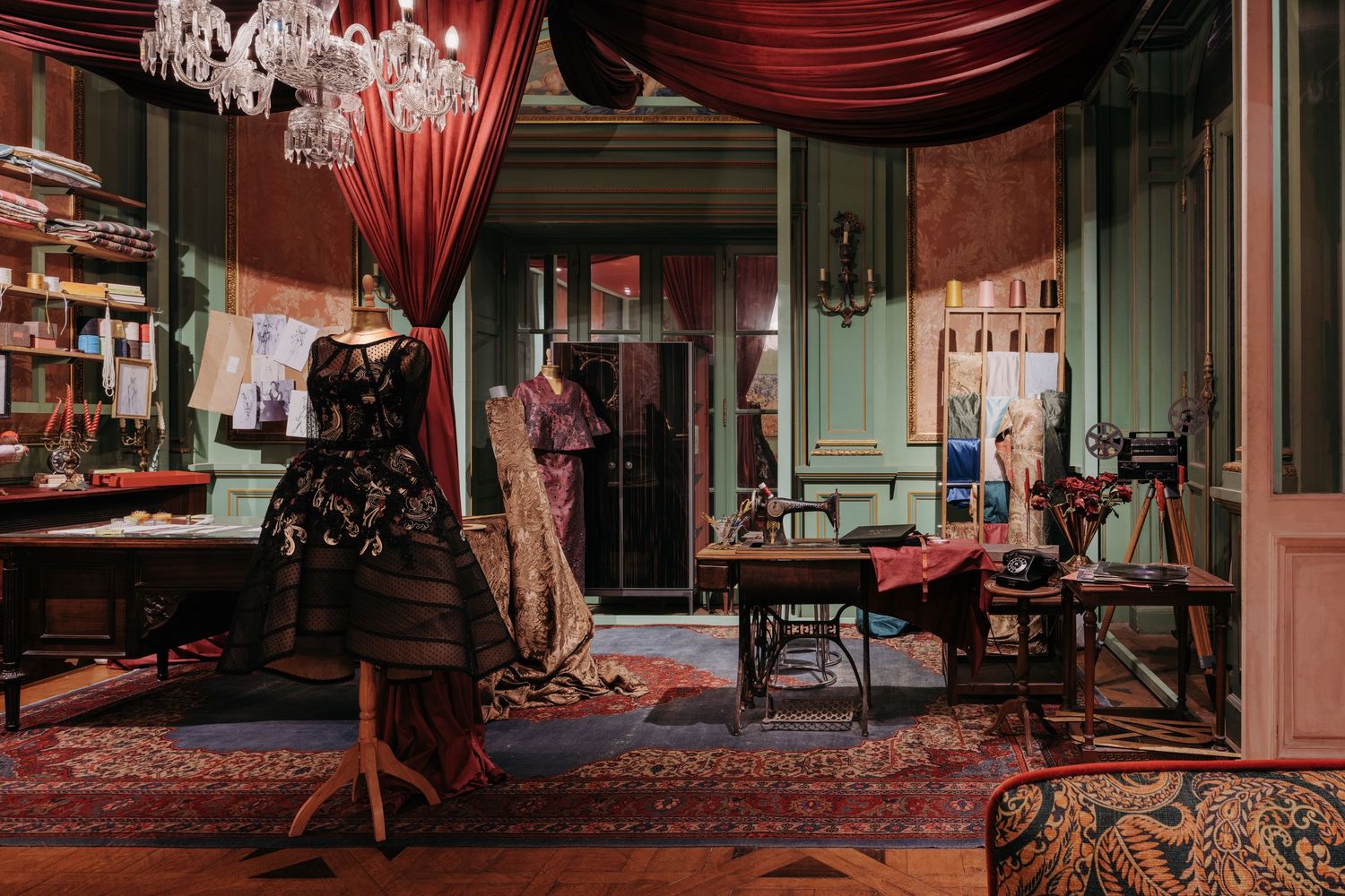 Elegant vintage fashion atelier with a black dress on a mannequin, sewing machine, and ornate red drapes.
