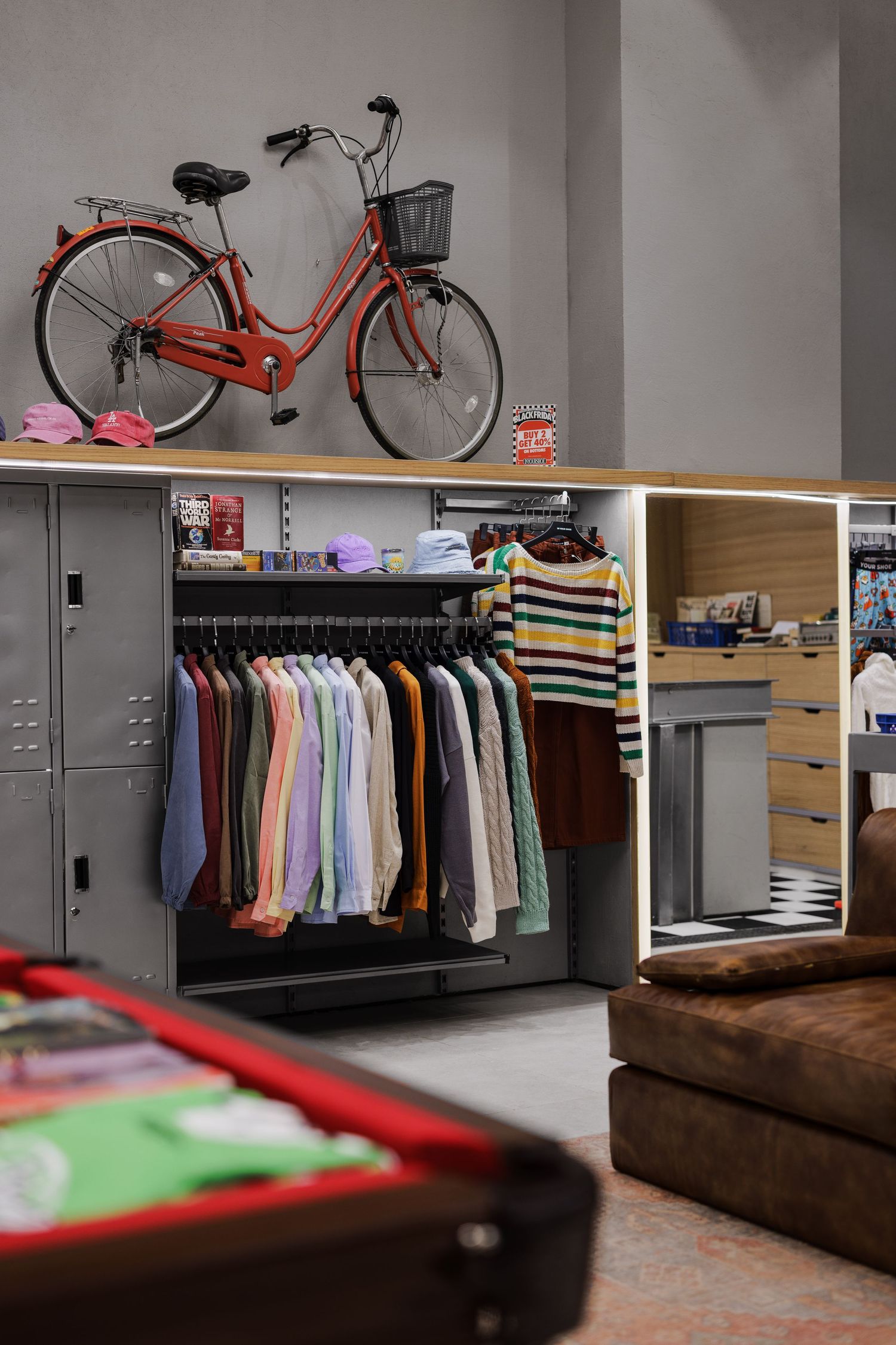Retail clothing store with red bicycle wall display and colorful garments on racks.