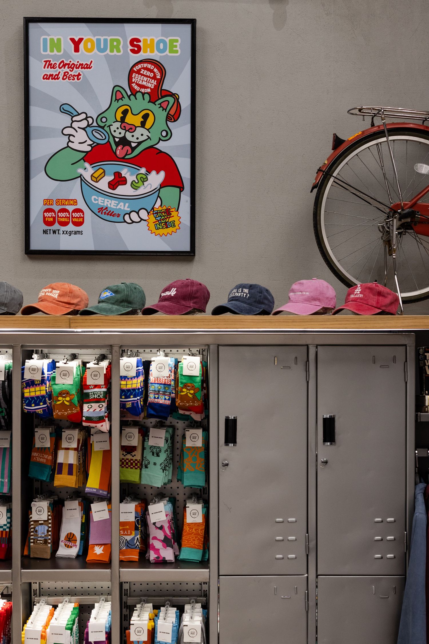 Colorful sock display with lockers, hats, a bicycle, and a fun cat cereal poster in a trendy shop.