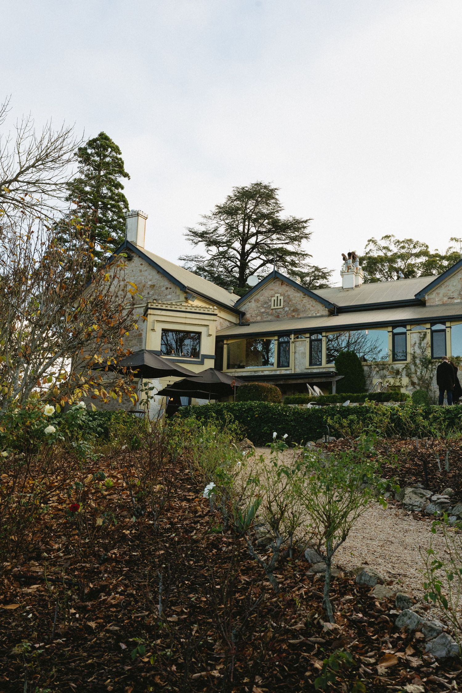 Four connected views of a modern gray house with dormers situated on a rocky hillside surrounded by autumn foliage.