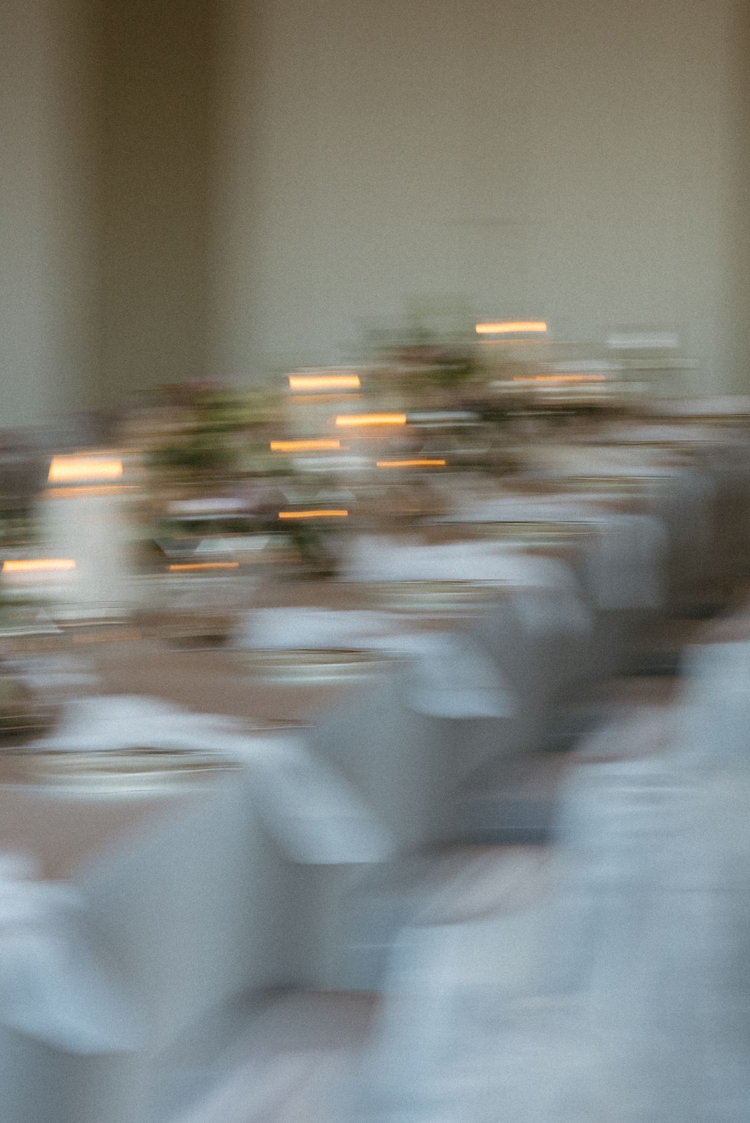 Abstract motion blur photograph shows figures in white creating a dreamy ethereal effect against neutral background.