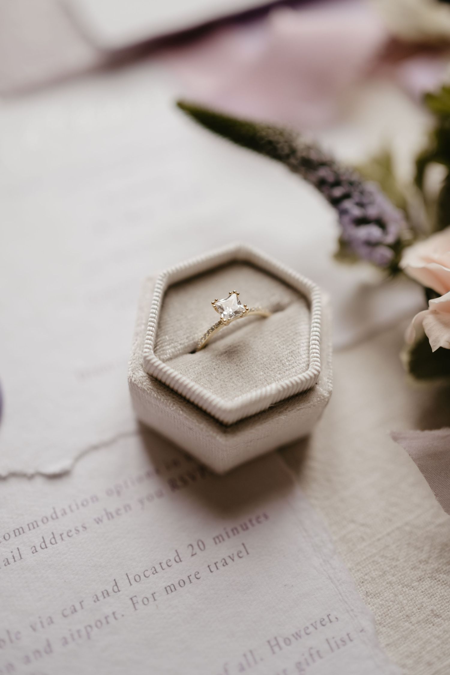 Engagement ring in hexagonal velvet box with delicate flowers and calligraphy paper.