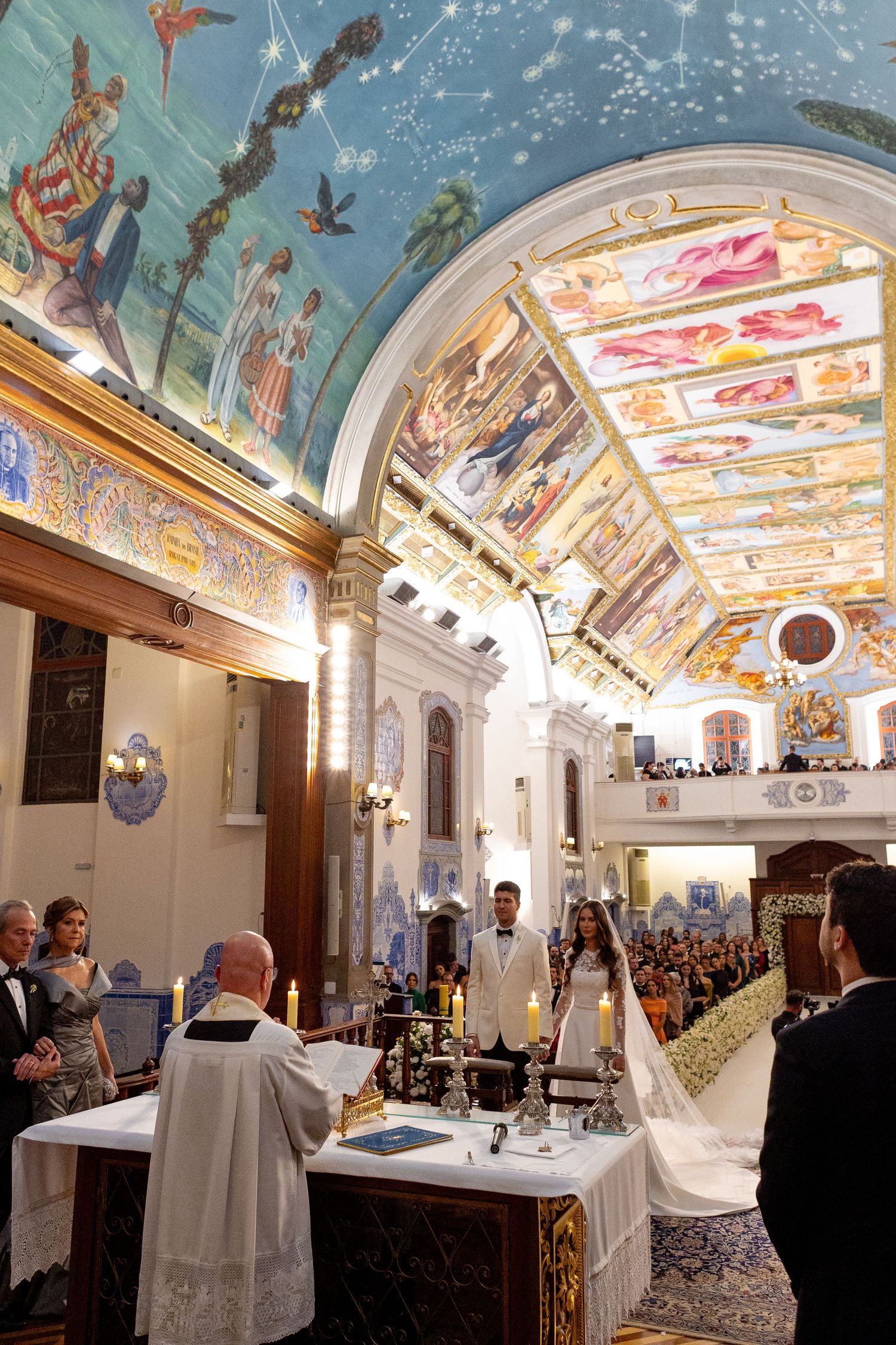 A panoramic view of an ornate ballroom with painted ceiling murals and elegant decor during a formal event.