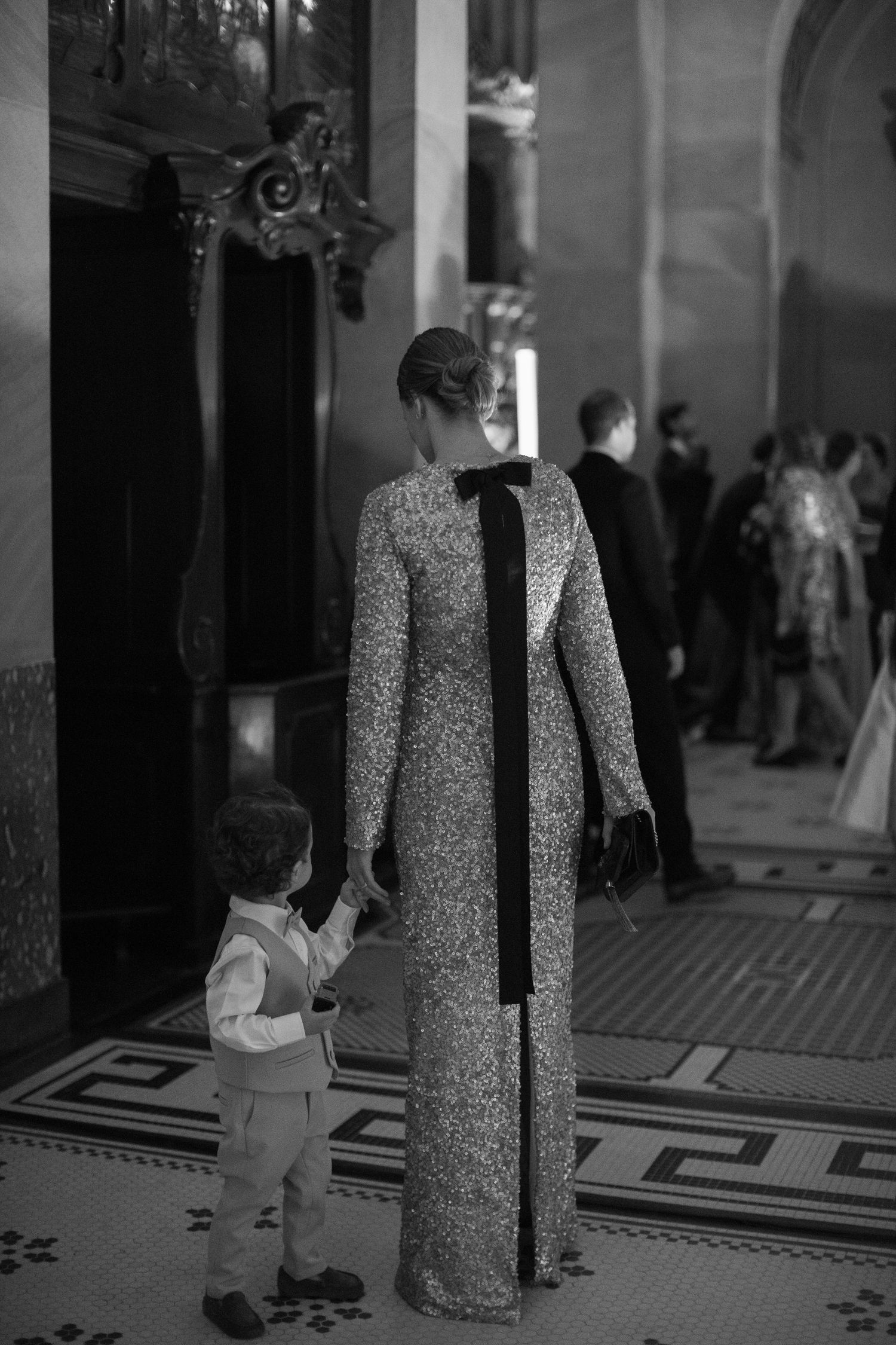 A black and white photo sequence shows a person in a patterned dress walking across a tiled floor.