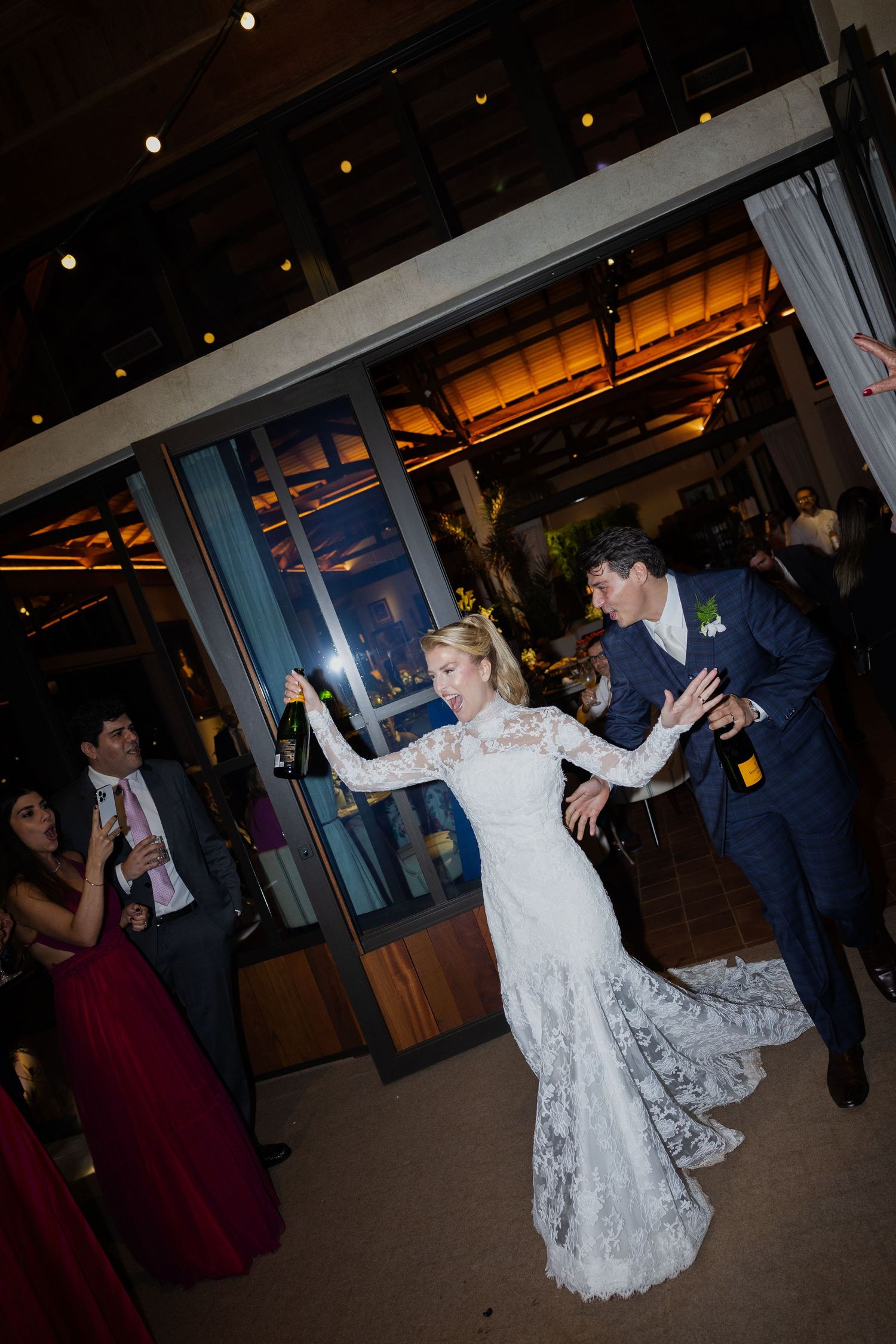 A couple shares their first dance at a wedding reception in a dimly lit venue with string lights overhead.