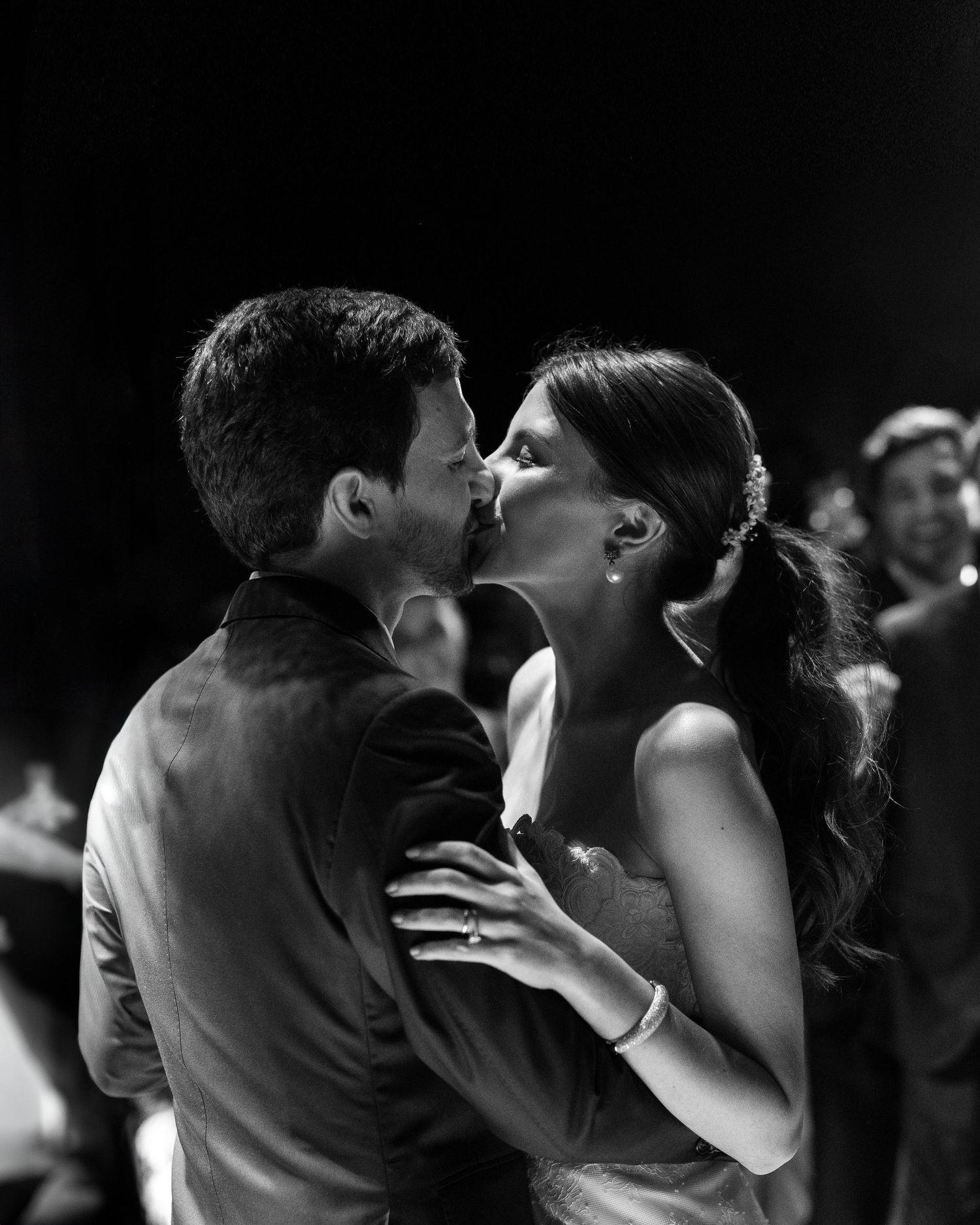 A romantic black and white photograph of a couple sharing a tender kiss on the dance floor.