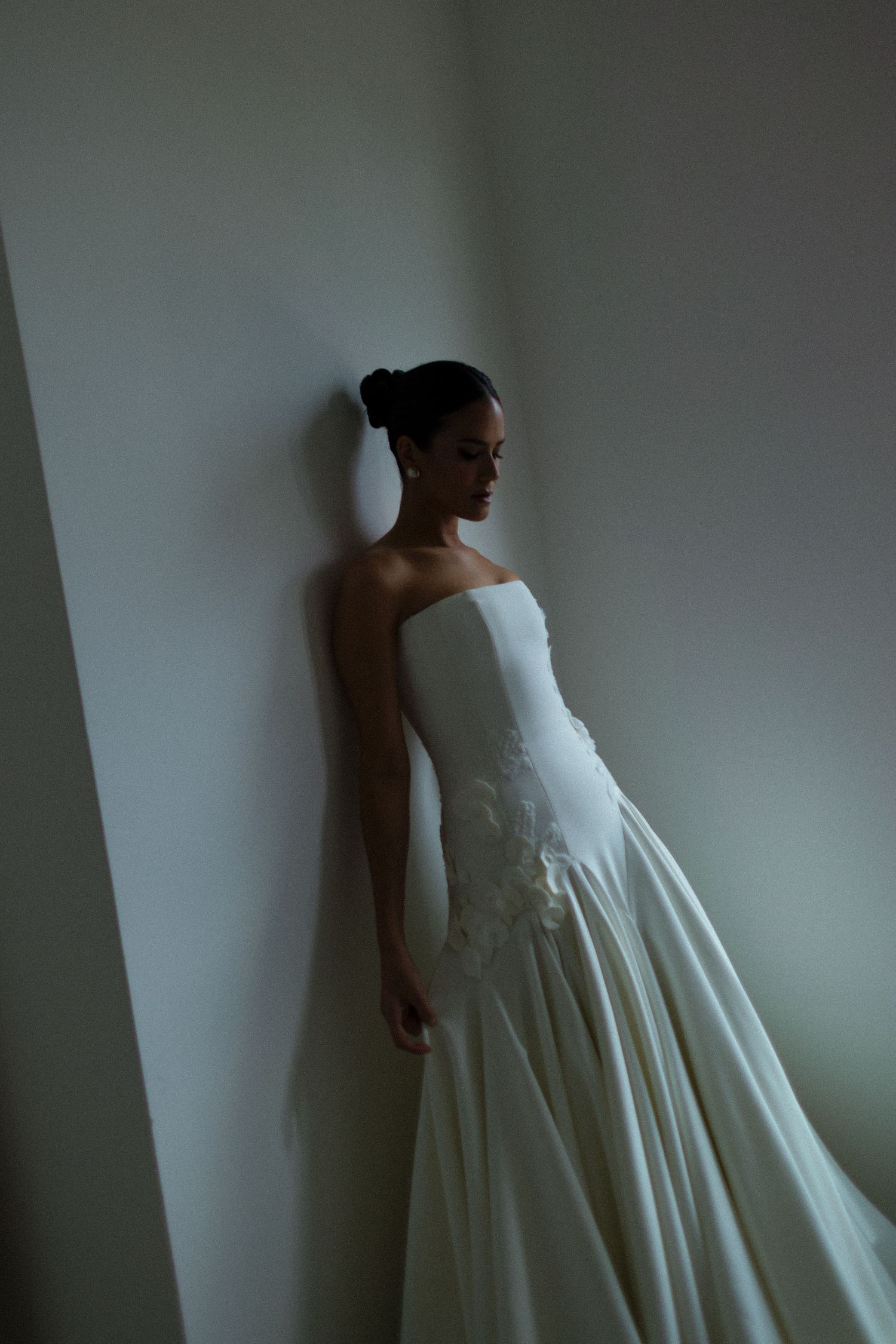 A person in a flowing white dress stands against a minimalist grey background in an artistic photography series.