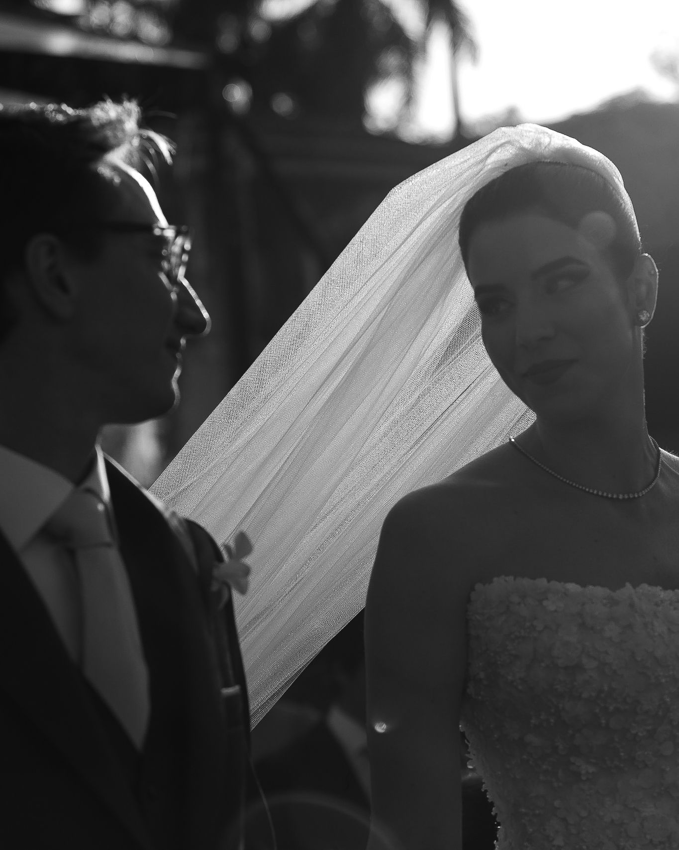 Black and white wedding portrait with flowing veil captured in dramatic lighting.