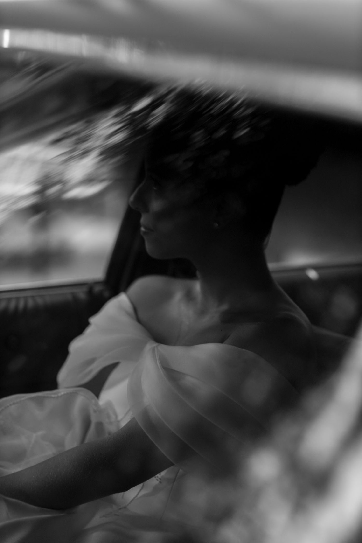 Artistic black and white photograph of a person in a car with blurred motion effects creating a dreamy atmosphere.