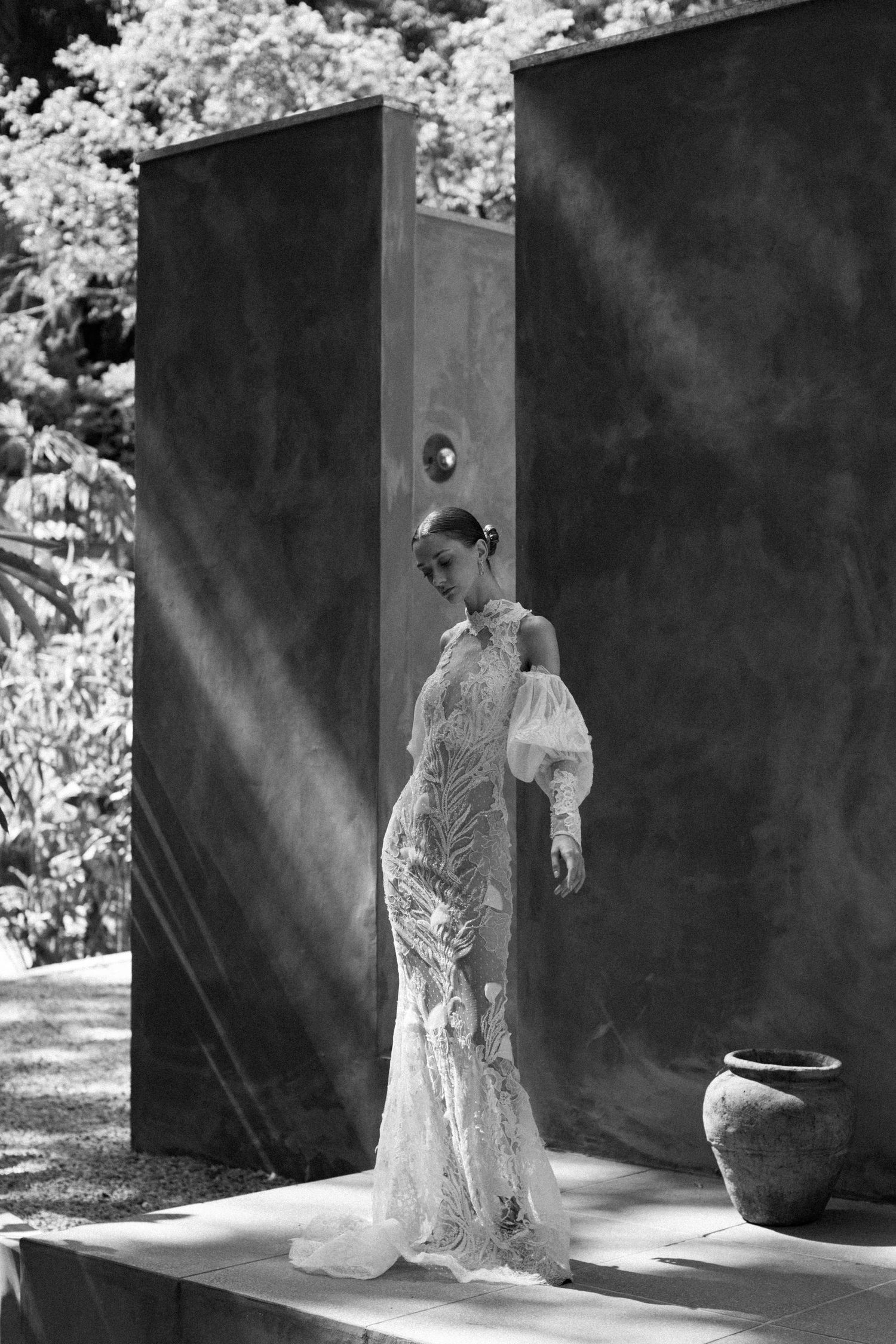 Elegant lace wedding dress with bishop sleeves captured in dramatic black and white photography.