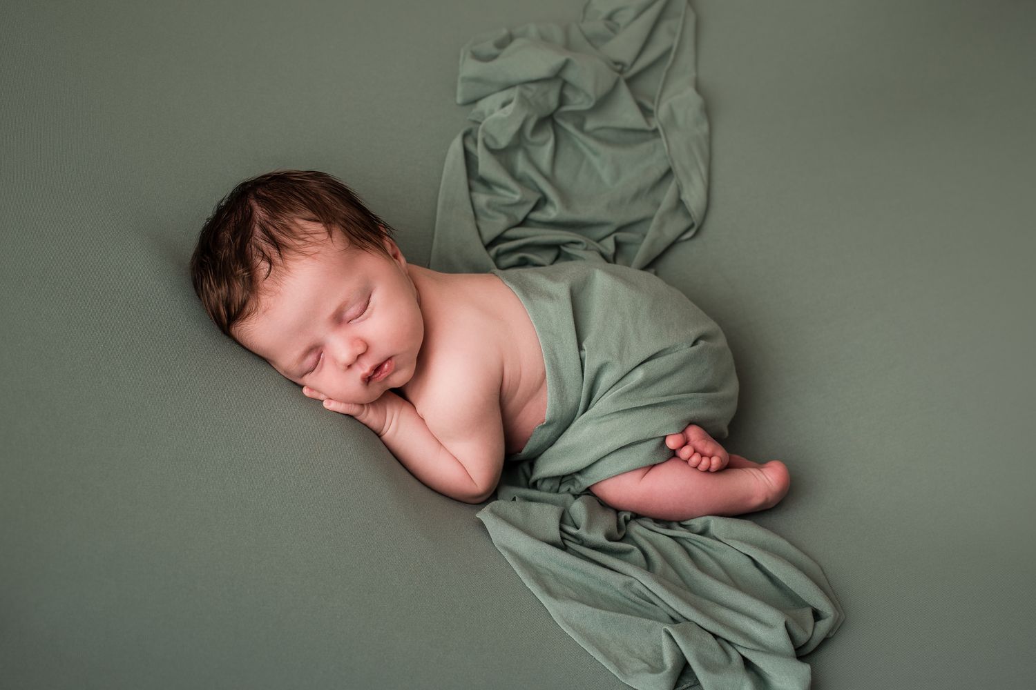 Geposeerde newborn foto van schattig slapende baby met donkere haren