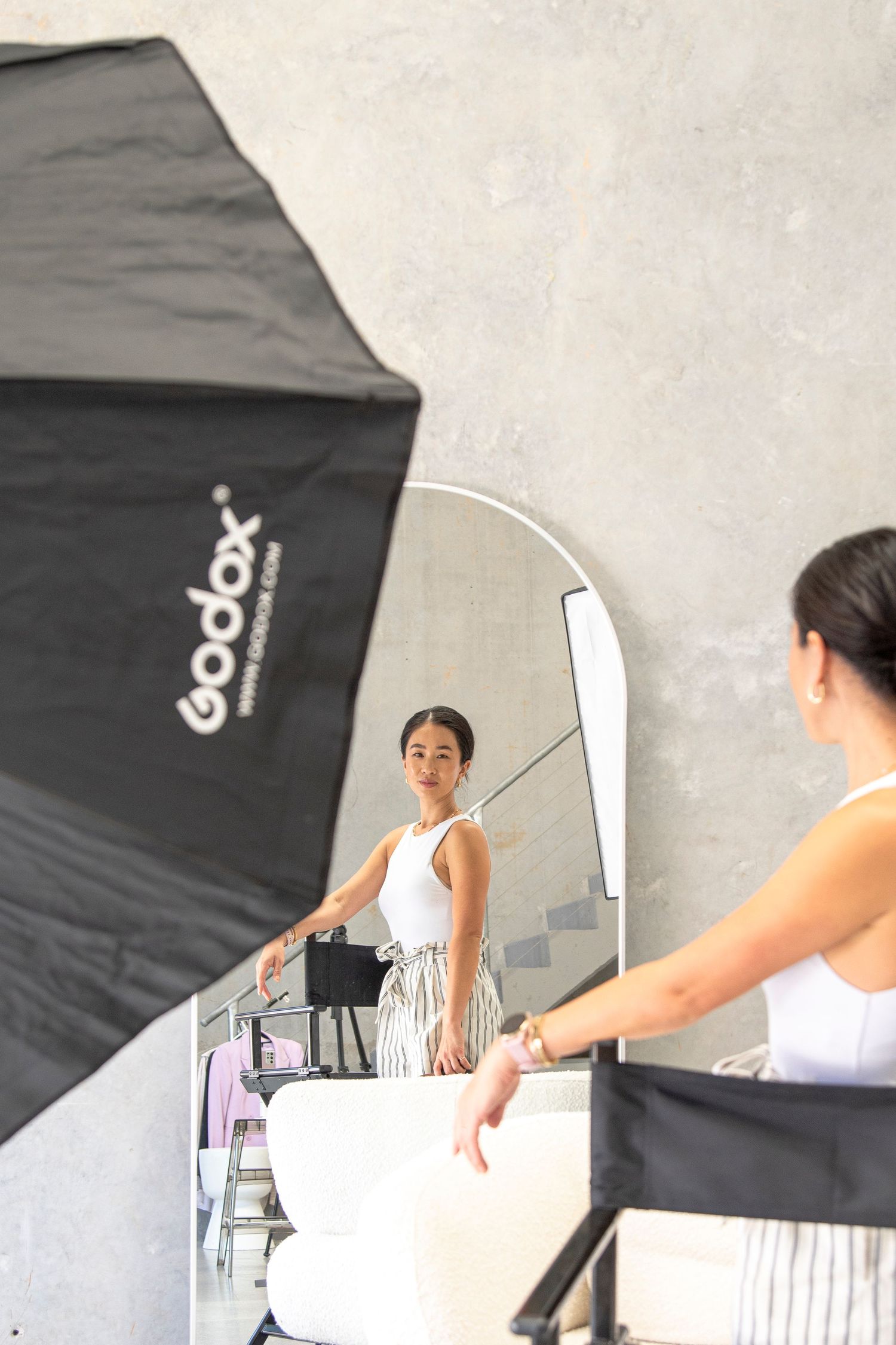 Behind-the-scenes photography setup with a Godox softbox and reflector in a studio setting with white walls.