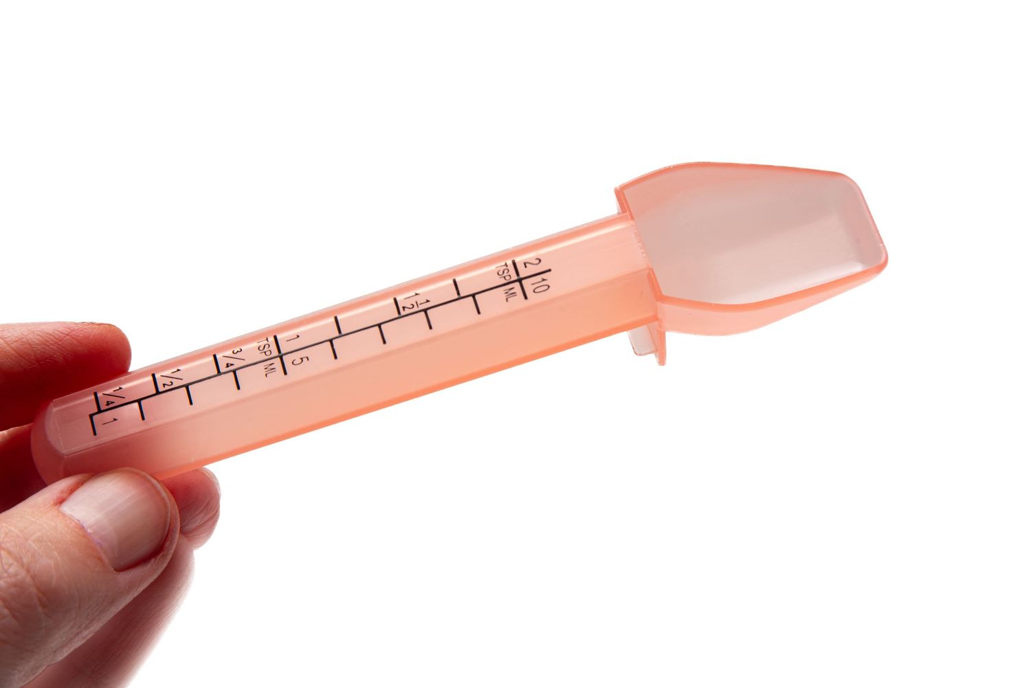 Fingers holding a liquid medicine dispenser spoon