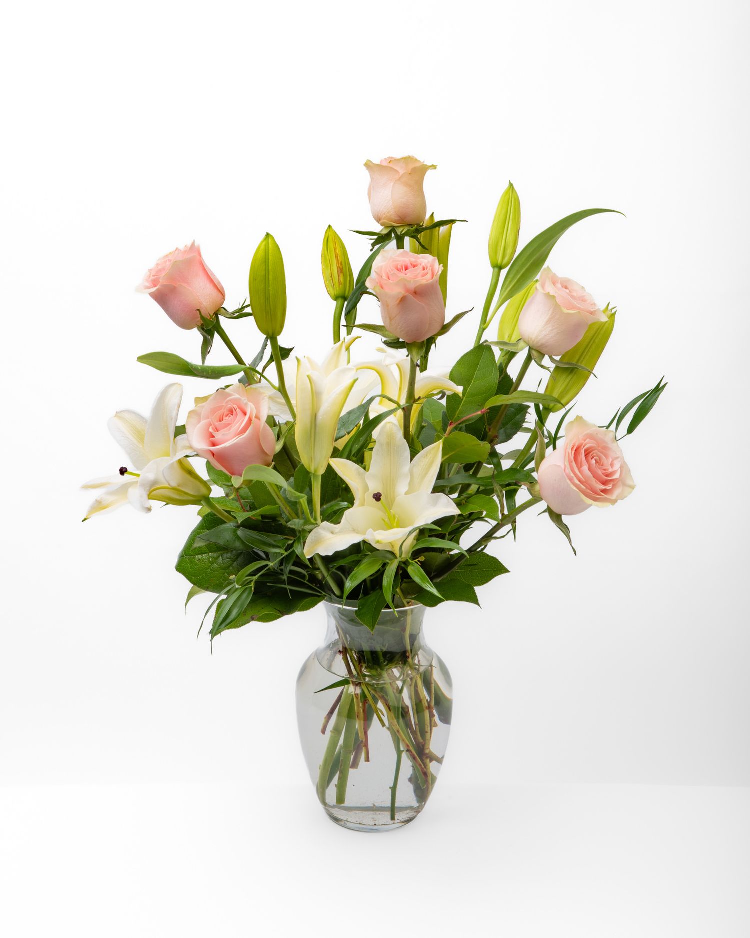Product photography image of a floral arrangement of pink roses and white lilies.