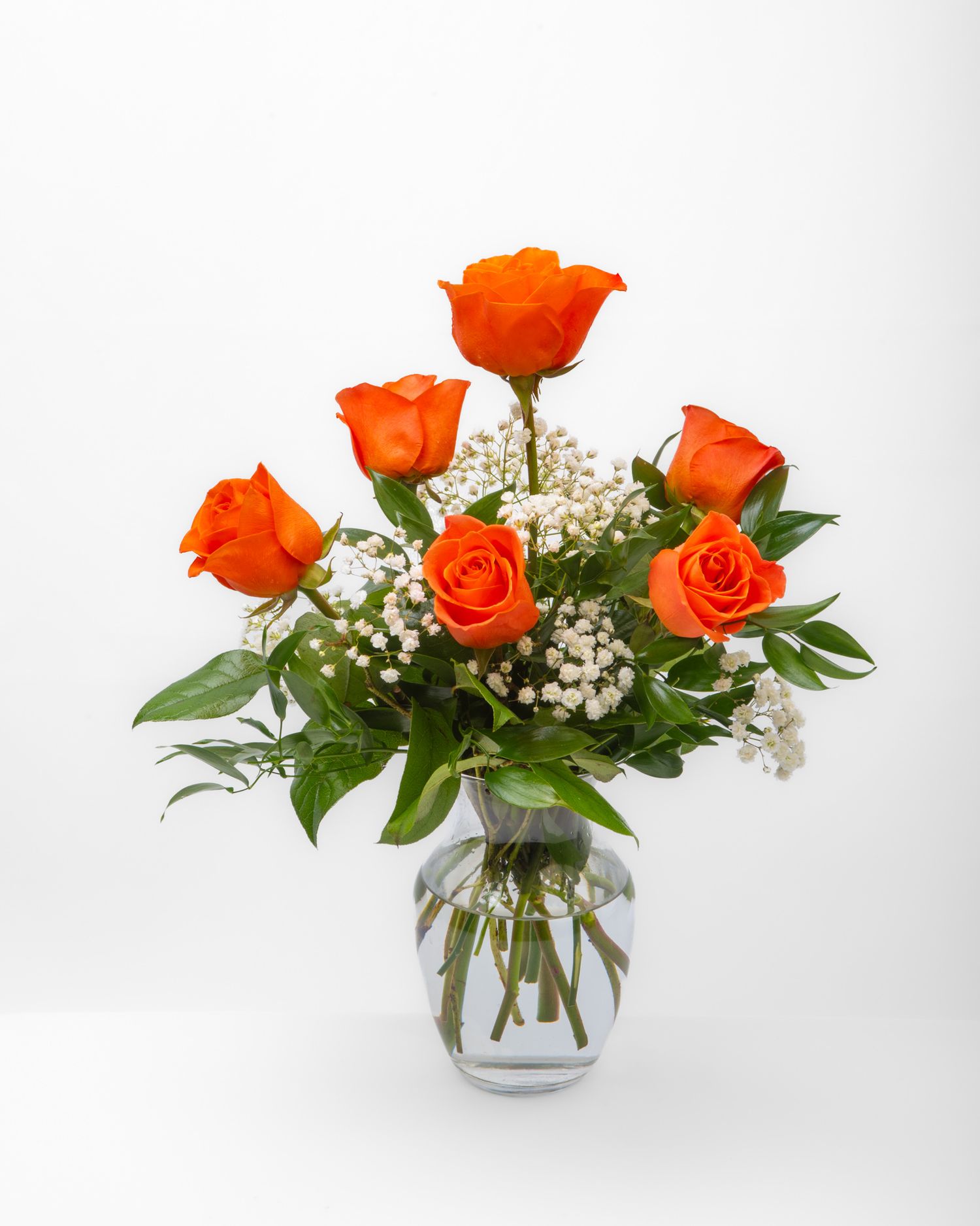 Six dozen orange roses with baby's breath in a glass vase.