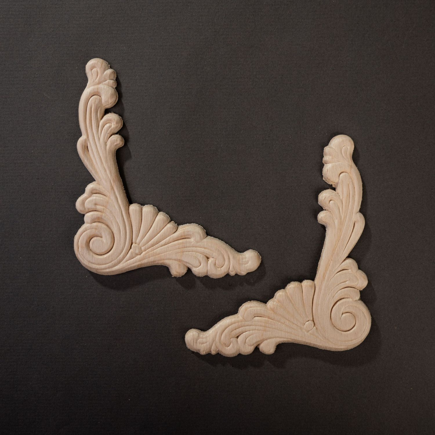 Mirror image wooden appliques on dark grey background photographed for a catalogue.