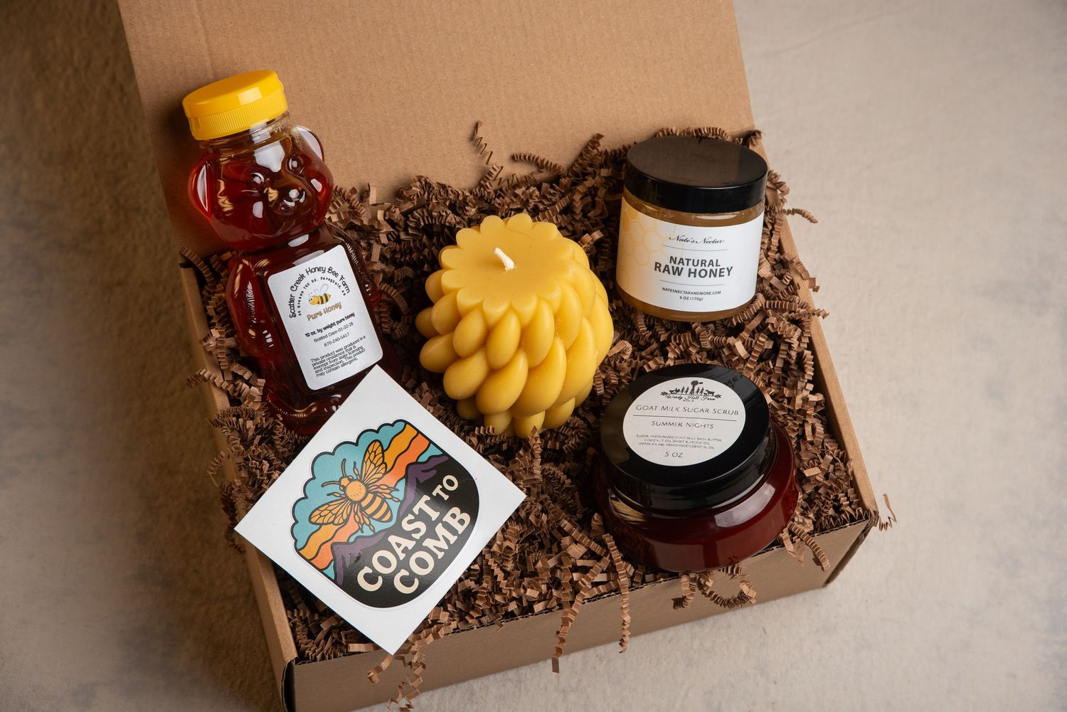 Photograph of honey and candles in a gift box.