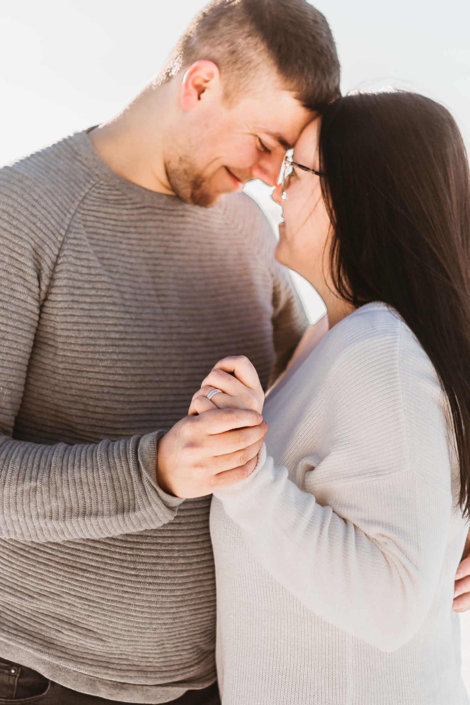 A romantic couple in gray sweaters share tender moments in a series of intimate poses against a white background.
