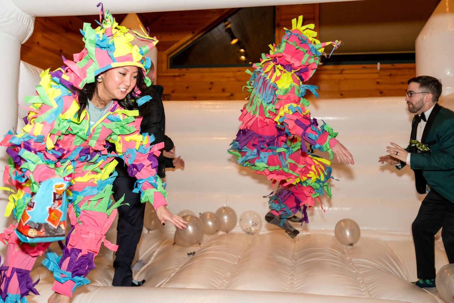 Wedding celebration featuring colorful piñata costumes and gold balloons in an indoor venue.