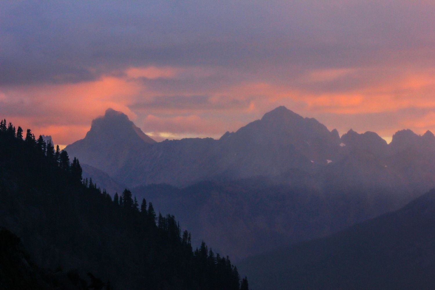 Mountain silhouettes against dramatic purple and orange sunset sky.