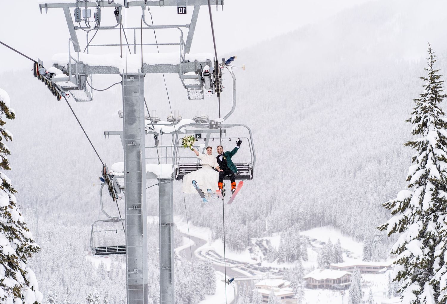 Ski lift chairs carry riders up a snowy mountain slope with snow-covered evergreen trees in winter.