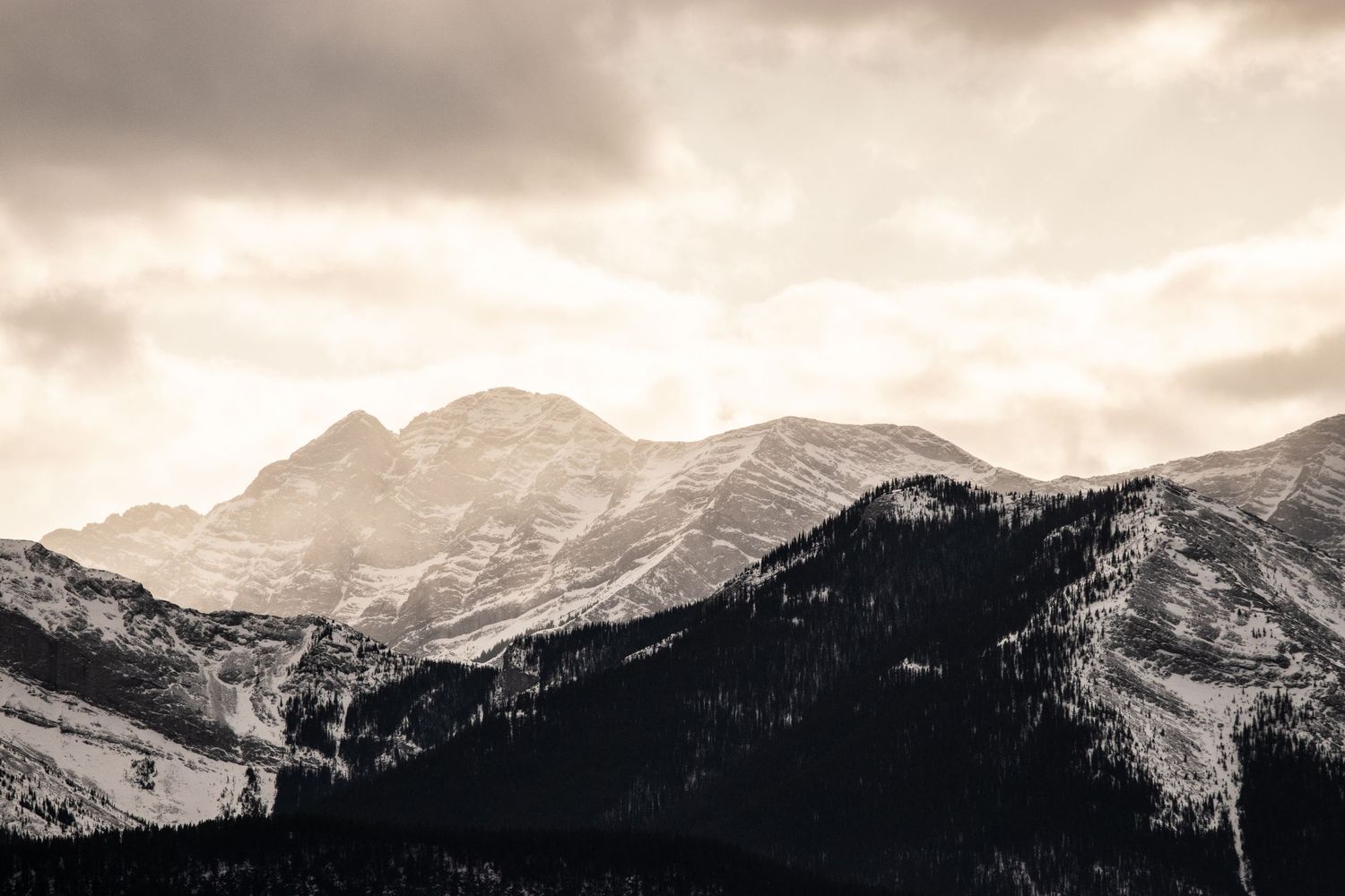 Monochromatic mountain landscape with rugged peaks and valleys under moody sky.