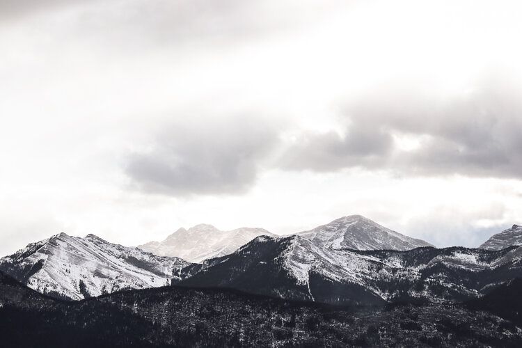 Snow-covered mountain range extends across horizon under moody overcast skies.
