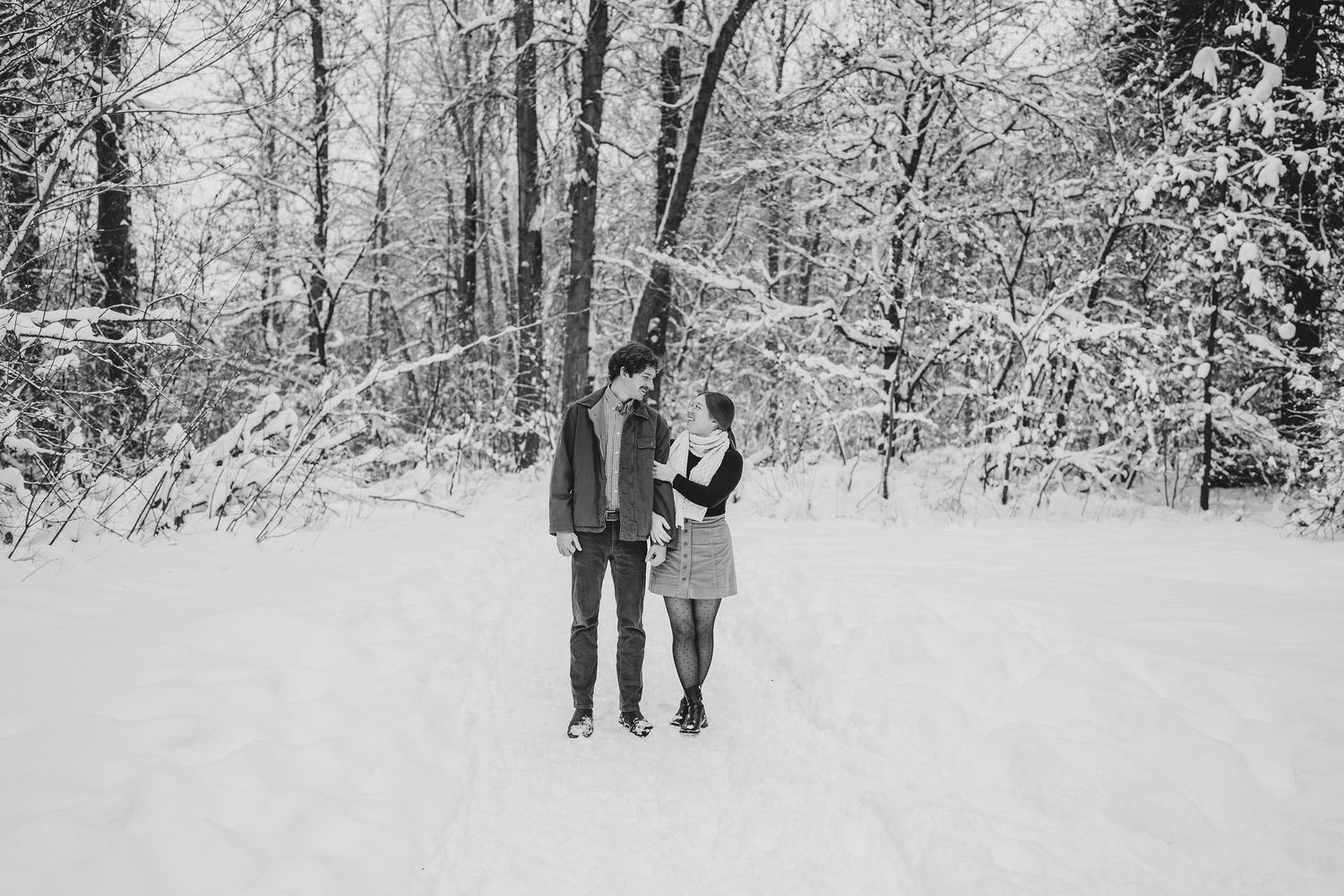 People walk through a snow covered forest path on a winter day as white flakes blanket the surrounding trees.  Leavenworth, WA