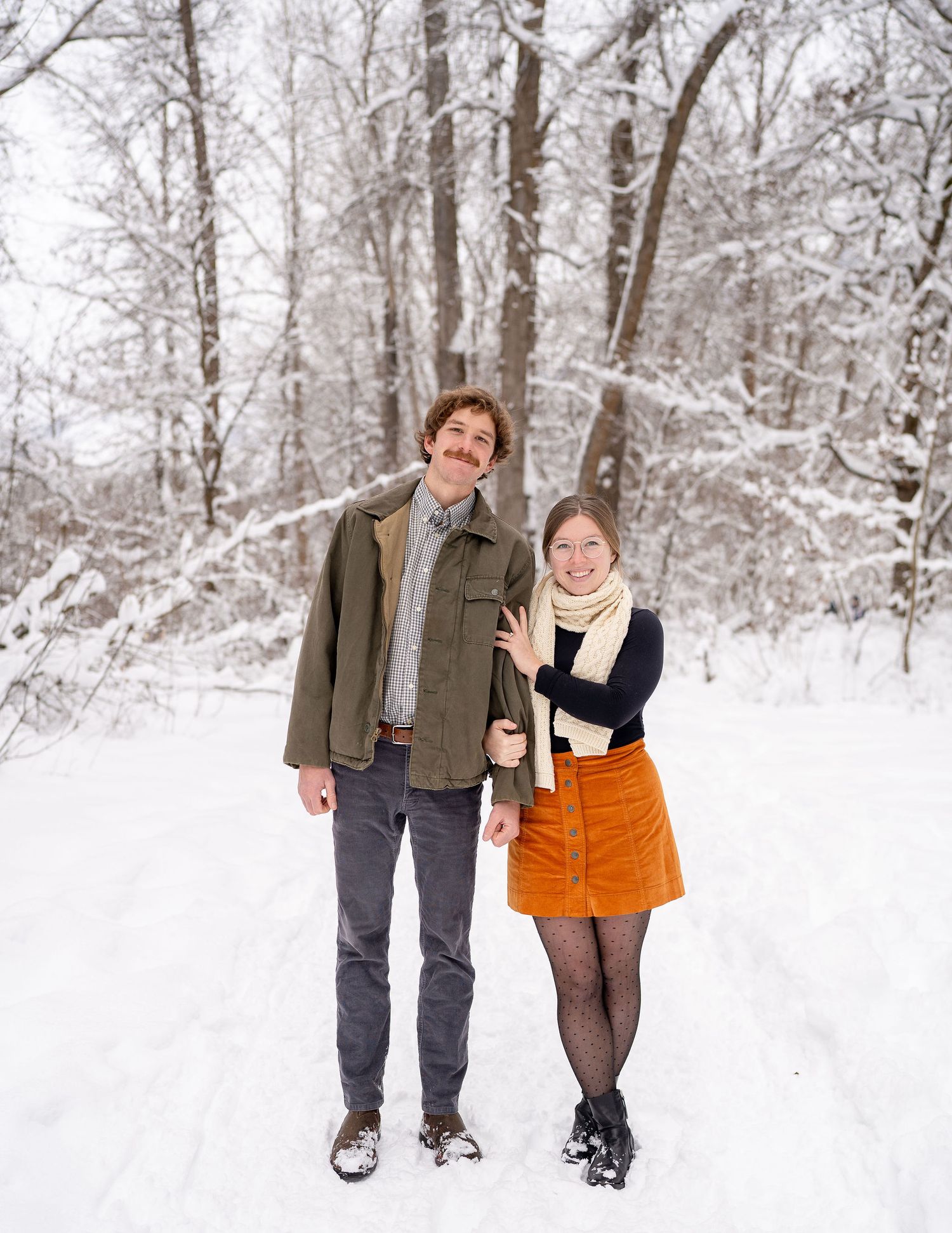 A couple walking through a snowy winter forest path while holding hands and smiling. Leavenworth, WA