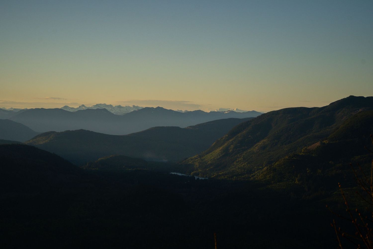 Silhouetted mountain ranges stretch into the distance under a gradient sunset sky.