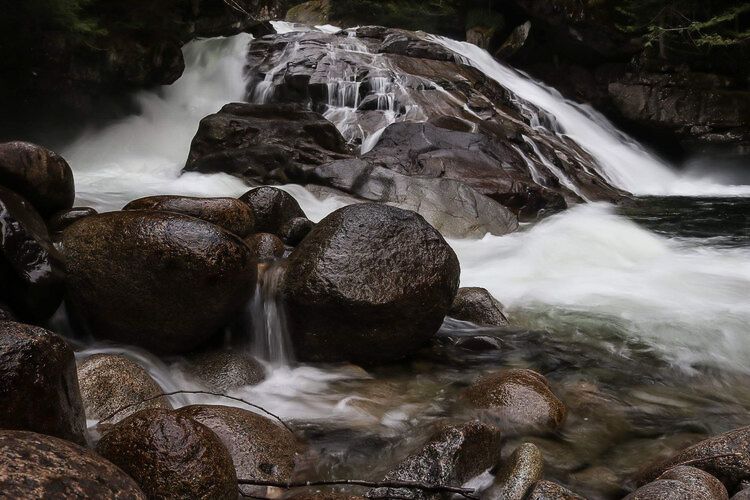 Fast-moving waterfall cascades over dark rocks in long exposure shot.